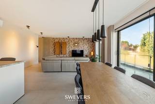 Voor meer info en foto’s, surf naar [www.swevers.be](http://www.swevers.be) — Dit instapklare appartement uit 2025 in Residentie Zwanenpark heeft een bewoonbare oppervlakte van 100 m² en bevindt zich op de eerste verdieping aan Kolmen 32A bus 4, centraal in Tessenderlo. Winkels, restaurants, scholen en openbaar vervoer liggen op wandelafstand, terwijl de snelweg zich op slechts 3,5 km bevindt. De lichtrijke leefruimte van 36,89 m² sluit direct aan op de praktische keuken van 9,11 m². Brede raampartijen geven toegang tot het ruime, westgerichte terras van 12,98 m² waar u geniet van de avondzon. Via de nachthal bereikt u twee slaapkamers van 12,03 m² en 10,02 m², de badkamer met ligbad en twee afzonderlijke toiletten. Met een inloopkast, wasberging, kelderberging van 3,45 m², lift, airco, alarm en een inbegrepen autostaanplaats geniet u van compleet wooncomfort. Maandelijkse kosten: € 112. Bel voor een afspraak naar 011 255 155. Bron bewoonbare oppervlakte: EPC-verslag.