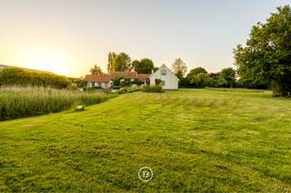 Deze karaktervolle hoeve bevindt zich in een discrete, landelijke omgeving en wordt aangeboden op een uitzonderlijk ruim perceel van in totaal 21.760 m². De combinatie van ruimte, groen en prachtige vergezichten over de omliggende weilanden zorgt voor een bijzonder aangename en rustige woonomgeving.<br /><br />De zuidgerichte tuin sluit mooi aan op de woning en beschikt over een terras en vijver. Daarnaast is er een ruime garage met plaats voor meerdere wagens, een werkruimte en voldoende opslagmogelijkheden voor tuinmateriaal.<br /><br />Binnenin is de woning praktisch en ruim opgevat. De lichtrijke woonkamer met hoog plafond vormt het hart van de woning en geniet, net als verschillende andere ruimtes, van een mooi contact met de groene omgeving. Verder beschikt de eigendom over een volledig uitgeruste keuken, zes slaapkamers en drie badkamers.<br /><br />Met een totale grondoppervlakte van 21.760 m² is dit een interessante eigendom voor wie op zoek is naar een karaktervolle hoeve met veel ruimte, privacy en een uitgesproken landelijk karakter.