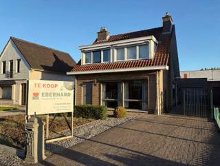 Dichtbij het centrum van De Klinge ligt deze heel goed onderhouden, vrijstaande woning. Ze is gebouwd in 1974 en kreeg er later een veranda bij. In 2022 werden rolluiken op zonneënergie geplaatst. In de inkomhal is er ook een gastentoilet. De woonkamer heeft grote ramen en krijgt daardoor veel lichtinval. De keuken is gescheiden van de leefruimte en ingericht met kasten en toestellen. Naast de keuken is er een handige berging. De veranda ligt achter de leefruimte en naast de keuken en geeft toegang tot de tuin. Boven zijn er 3 comfortabele slaapkamers en een badkamer met zitbad, lavabo en wc. De zolder heeft een uittrekbare trap en kan gebruikt worden als berging. Onder de woning loopt een kruipkelder. De garage is ruim en heeft zowel een poort als een zijdeur én er ligt zelfs verwarming. Aanpalend aan de garage is er een buitenberging. De tuin is Zuidwest gericht en biedt veel privacy. De woning heeft een betonvloer tussen gelijkvloers en verdieping. Er is centrale verwarming in alle kamers. Bijkomend is er nog een kachel waar vroeger de open haard was. De oprit is netjes aangelegd met klinkers en een hek sluit het achterste deel af. Vraag vandaag uw bezoek aan op 03 779 69 29 of contact@eberhardvastgoed.be