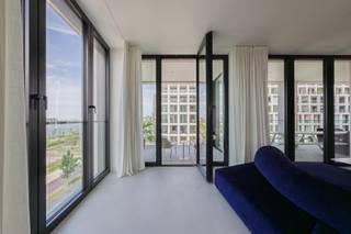 <p><strong>Exclusief appartement in het gebouw van Max Dudler, Nieuw Zuid</strong></p>
<p>Op één van de meest gegeerde locaties van Nieuw Zuid, in het karakteristieke gebouw ontworpen door architect Max Dudler, ligt dit uitzonderlijke appartement. Een zeldzame gevelbreedte zorgt voor een frontaal en ononderbroken zicht op de Schelde, zowel vanuit de leefruimte als vanuit de keuken.</p>
<p>De grote terrassen aan beide zijden van het appartement bieden een weids uitzicht over de vernieuwde Kaaien van Antwerpen en de historische binnenstad. Bij zonsopgang én -ondergang verandert het panorama over de rivier en de stad steeds opnieuw van sfeer.</p>
<p>Binnen vormen de lichte, open leefruimte en de keuken het kloppende hart van de woning. Vloer-tot-plafondramen laten het daglicht ongehinderd naar binnen stromen, terwijl notelaar en marmer zorgen voor een tijdloze, warme uitstraling. De keuken, met een imposant kookeiland in marmer, is even functioneel als esthetisch verfijnd.</p>
<p>De mastersuite vormt een privé-retraite met een dressing en een badkamer met vrijstaand bad, inloopdouche en dubbele wastafel, stijlvol afgewerkt met Vola-kranen. Twee bijkomende slaapkamers, bediend door een tweede volwaardige douchekamer, maken het appartement even geschikt voor een gezin als voor wie nood heeft aan ruimte voor gasten of een thuiskantoor.</p>
<p>Doorheen het hele appartement getuigt de materiaalkeuze van een verfijnde, doordachte afwerking tot in het kleinste detail. Het wooncomfort wordt vervolledigd met drie parkeerplaatsen en een ruime kelderberging.</p>
<p>Wonen op Nieuw Zuid betekent wonen aan de oever van de Schelde, met de vernieuwde kaaien en de historische stad binnen handbereik, in een gebouw van uitgesproken architecturale kwaliteit. Een unieke kans voor wie ruimte, licht en uitzicht zoekt in Antwerpen.</p>