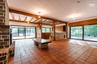 Op een bijzonder residentiële locatie, in een uitzonderlijk groene straat gekenmerkt door hoogstammige bomen en verschillende kasteeldomeinen, bevindt zich deze bijzonder ruime bungalow met een uitgesproken modernistisch karakter.<br /><br />De ligging combineert rust en privacy met een uitzonderlijk goede MOBI-score en een bijzonder vlotte bereikbaarheid. Aan de overzijde van de straat bevindt zich een apotheek, terwijl verderop in de straat zowel Colruyt als Delhaize (open tot 20 uur, ook op zondag), een tankstation, kleinhandel en horeca terug te vinden zijn. Meerdere scholen bevinden zich op wandelafstand. De op- en afrit van de R4 ligt op amper 2 minuten rijden en het centrum van Gent is met de fiets in ongeveer 12 minuten bereikbaar.<br /><br />De bungalow onderscheidt zich in de eerste plaats door zijn uitzonderlijke volumes. Niet alleen de leefruimte, maar ook de keuken, slaapkamers en garage zijn bijzonder ruim bemeten. De uitzonderlijk hoge plafonds en de overvloed aan natuurlijk licht versterken het open en ruimtelijke karakter van de woning. Bovendien geniet u vanuit vrijwel de volledige woning van zicht op het omliggende groen.<br /><br />Vanuit zowel de volledige leefruimte als de keuken geniet u van een prachtig zicht op de zuidgerichte tuin. Deze is bijzonder gezellig aangelegd en biedt dankzij het vele groen een hoge mate van privacy. Ook aan de straatzijde wordt de woning door de groene omgeving mooi gebufferd, waardoor het private karakter extra wordt benadrukt.<br /><br />Een absolute troef is de uitzonderlijk grote garage. Door haar afmetingen kan deze zonder overdrijven als een klein atelier worden beschouwd. Ook de garagepoort is royaal gedimensioneerd en biedt toegang aan nagenoeg elke bestelwagen.<br /><br />De woning beschikt momenteel over vloerverwarming en de brede deuropeningen zijn geschikt met het oog op eventuele rolstoeltoegankelijkheid. Ook het EPC-label C vormt voor een woning met dit renovatiepotentieel een interessante uitgangspositie.<br /><br />De bungalow dient gerenoveerd te worden, waarbij onder meer het dak en het interieur aangepakt moeten worden. Precies daarin schuilt echter de bijzondere opportuniteit: dankzij de royale volumes, hoge plafonds, het vele natuurlijke licht en het alomtegenwoordige zicht op groen kan deze woning na renovatie uitgroeien tot een uitzonderlijk modernistisch pareltje met een uniek loftkarakter.<br /><br />Een zeldzame eigendom voor wie op zoek is naar ruimte, licht, privacy en architecturaal potentieel op een bijzonder residentiële locatie vlak bij Gent.