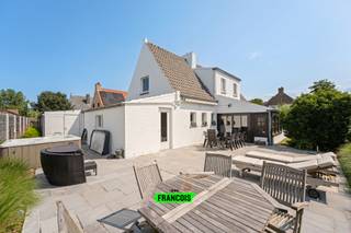 In het rustige en idyllische De Wandelaar, een doodlopende straat waar enkel plaatselijke bewoners passeren, vinden we deze charmante woning die perfect de balans vindt tussen privacy en verbondenheid. Hier woont u in alle rust, terwijl het bruisende stadsleven, de gezellige handelszaken, de polders én het strand met de zeedijk zich op wandel- en fietsafstand bevinden. Een unieke ligging die u het beste van twee werelden biedt: sereniteit en nabijheid.<br /><br />Bij aankomst geniet u van de vlotte parkeermogelijkheden: voor de woning is er steeds plaats, maar ook op de privatieve oprit is ruimte voor meerdere wagens. De garage biedt niet alleen extra parkeercomfort, maar ook royale opbergruimte.<br /><br />We betreden de woning via de inkomhal met handige bergruimte en apart toilet. Van hieruit leiden we u naar de lichtrijke woonkamer, opgedeeld in een gezellige living, een eetplaats en een vaste veranda met zicht op de prachtig zongerichte tuin. Dankzij de kachel geniet u hier ook in de winter van een warme, huiselijke sfeer. De open keuken is uitgerust met hedendaagse voorzieningen, waardoor koken hier een plezier wordt.<br /><br />Op het gelijkvloers vinden we daarnaast een extra berging, een eerste badkamer, een saunakamer, een bureauruimte en een eerste slaapkamer, ideaal voor wie gelijkvloers wil wonen of gasten in alle comfort wil ontvangen. De eerste verdieping biedt plaats aan drie bijkomende slaapkamers, waarvan twee ruime en één kinderkamer, en een tweede badkamer.<br /><br />Extra pluspunten: de woning kent geen renovatieverplichting, de elektrische installatie is volledig conform gekeurd en de jacuzzi in de tuin maakt deel uit van de verkoop. Hier geniet u in alle privacy, omgeven door groen en zon.<br /><br />Deze woning is een perfecte uitvalsbasis voor wie houdt van rust, maar de nabijheid van stad, strand en natuur weet te waarderen. Mis deze kans niet en plan vandaag nog uw bezoek!<br /><br />