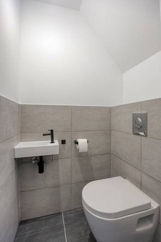 <p>Bij het betreden van de woning komt u binnen in de inkomhal, waar zich de trap naar de eerste verdieping bevindt, evenals een afzonderlijk gastentoilet. Vanuit de inkomhal bereikt u de zeer ruime leefruimte via een zwarte metalen deur met glaspartijen. Achteraan zijn de aansluitingen voorzien om zelf een keuken te plaatsen, de keuken dient nog door de koper zelf te worden aangekocht en geïnstalleerd. Boven de keuken zorgt een glazen lichtstraat voor een aangename en overvloedige lichtinval.</p>
<p>Verder is er een technische ruimte die tevens kan dienen als berging. Hier bevinden zich de aansluitingen voor de vloerverwarming, die zowel kan verwarmen als koelen (warmtepomp), de warmtepompboiler en de pomp van de regenwaterput.</p>
<p>Op de eerste verdieping zijn er twee slaapkamers en een badkamer. De badkamer is uitgerust met een inloopdouche, een toilet en de nodige voorzieningen voor een badkamermeubel. Daarnaast is er ook een beperkte zolderberging aanwezig, bereikbaar via een uitschuifbare trap.</p>
<p>Achteraan de woning bevindt zich een gezellig tuintje met een verhard terras. Aansluitend is er de mogelijkheid om een wagen te parkeren, al de aansluitingen voor een elektrische laadpaal zijn voorzien. In de kelder is bovendien een praktische kelderberging aanwezig.</p>
<p>Troeven van de woning:<br />✅ Extreem gunstig EPC met A+ label.<br />✅ Voldoende zonnepanelen.<br />✅ Driedubbele beglazing.<br />✅ Regenwaterput van 7.500 liter, aangesloten op toiletten en buitenkraan.<br />✅ Alle keuringen zijn conform.<br />✅ Keuken aan 6% btw.</p>
<p>En het grootste voordeel van allemaal: deze woning wordt te koop aangeboden onder registratierechten, niet onder btw!</p>
<p>Aarzel niet en contacteer ons vandaag nog voor een bezichtiging op het nummer 0499/30.87.87 of via info@immo-bosmans.be</p>