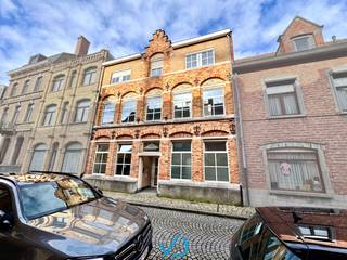 In de D'Hondtstraat, op een uiterst centrale locatie in het hart van Ieper, vinden we deze bijzonder ruime woning terug. Dankzij haar strategische ligging bereik je werkelijk alles binnen vijf minuten te voet: van winkels en scholen tot openbaar vervoer en andere voorzieningen. Deze eigendom biedt niet alleen veel ruimte, maar ook een waaier aan mogelijkheden, zowel voor particuliere bewoning als voor gemengd gebruik of een combinatie van wonen en werken. <br /><br />Bij het binnenkomen via de inkomhal valt de grootte van de woning meteen op. Aan de rechterzijde bevinden zich de toiletten, terwijl je aan de ander kant een eerste kamer aantreft. Deze ruimte kan moeiteloos geïntegreerd worden in de leefruimte, of dienst doen als bureauruimte, parktijk of ontspanningsruimte. Verder vinden we op het gelijkvloers een voormalige polyvalente ruimte, die zich uitstekend leent tot uiteenlopende invullingen, afhankelijk van je noden en wensen. Vanuit de leefruimte heb je bovendien toegang tot een droge kelder, ideaal als extra opslagruimte of wijnkelder. <br /><br />Op de eerste verdieping bevinden zich twee zeer ruime kamers die vandaag als slaapkamers zijn ingericht, maar net zo goed andere functies kan vervullen. OP de tweede verdieping werd in het verleden een apart appartement ingericht, met twee bijkomende kamers, waarvan één voorzien werd van een kitchenette. aansluitend bevindt zich de badkamer, uitgerust met ligbad en een lavabo. Tot slot biedt de zolderverdieping, bereikbaar via een valtrap, nog extra ruimte voor opslag of een creatieve invulling. <br /><br />De woning is technisch goed uitgerust, met centrale verwarming op aardgas, aluminium ramen met hoogrendementsbeglazing en een asbestveilig attest. Bovendien is er potentieel om een dakterras te creëren, wat de beleving van de woning nog aangenamer maakt. Wie nood heeft aan parkeergelegenheid kan bovendien een overdekte autostaanplaats optioneel aankopen met afgesloten poort achteraan de woning. Een directe toegang tot de woning kan hier vlot voorzien worden. <br /><br />Kortom, dit pand is een echte opportuniteit voor wie op zoek is naar een woning met veel ruimte, karakter én mogelijkheden op een topligging in Ieper. Laat je verrassen door het potentieel tijdens een bezoek en ontdek zelf hoe deze woning zich aanpast aan jouw toekomstplannen.  