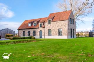 Op een uitzonderlijk perceel van 25.300 m² bevindt zich deze energiezuinige, volledig gerenoveerde woning met bijgebouw, ruime loods en uitgestrekte weilanden met diverse stallingen – een ideale eigendom voor wie ruimte en comfort wil combineren.<br /><br />Via de lange oprit bereikt u de royale parkeergelegenheid. De loods/stalling van ca. 200 m² beschikt over twee sectionale poorten, waardoor overdekt parkeren perfect mogelijk is. Er is ook een laadpaal voorzien. Een ander gedeelte van de loods biedt extra bergruimte en kan gebruikt worden voor het stallen van de dieren.<br /><br />De woning zelf telt drie aparte ingangen. De centrale inkomhal geeft links toegang tot de gezellige leefruimte met eetplaats en een volledig uitgeruste open keuken, die aansluit op de praktische wasplaats. Rechts bevindt zich een eerste slaapkamer en een ruime badkamer met ligbad, inloopdouche en dubbele lavabo. Op de verdieping zijn er nog twee slaapkamers, een biljartkamer (eenvoudig om te vormen tot vierde slaapkamer), een berging en een tweede badkamer met douche. De zolder, bereikbaar via een uittrekbare trap, biedt bijkomende opbergruimte.<br /><br />Achteraan geniet u van een grote groentetuin met serre, aan de zuidkant is er een terras. De woning is afgewerkt met ingemaakte kasten, parketvloeren in leefruimte en slaapkamers, vloerverwarming via geothermische warmtepomp, alarmsysteem, shutters, ingebouwde verlichting, een regenwaterput van 30.000 liter, grondwaterput én maar liefst 48 zonnepanelen.<br /><br />Het bijgebouw doet dienst als multifunctionele ontspanningsruimte met extra bergruimte (geen mogelijkheid tot extra domicilie). Een unieke eigendom met tal van mogelijkheden in een rustige, groene omgeving.<br />Hou je van privacy en woon je graag te midden van het groen maar toch op korte afstand van winkels, de basisschool, het station van Hansbeke en de autostrade? Meer info via Palestraat21.rosseel.be