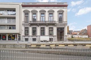 Gelegen in het hart van Kortrijk, biedt dit indrukwekkende kantoorpand een royale bruikbare oppervlakte van 456,7 m². Het historische karakter van het gebouw wordt op elegante wijze gecombineerd met moderne functionaliteiten, waardoor het een ideale werkplek is.Bij binnenkomst valt meteen de ruime en goed verlichte receptie op, perfect om gasten te ontvangen. De majestueuze houten trappen geven het interieur een klassieke uitstraling en leiden naar verschillende kantoorruimtes. Deze ruimtes zijn voorzien van hoge plafonds en grote ramen, wat zorgt voor een aangename en lichte werksfeer.Het pand beschikt over meerdere stijlvolle vergaderruimtes, elk met een uniek karakter. De parketvloeren en verfijnde afwerking benadrukken de kwaliteit en klasse van het gebouw. Daarnaast zijn er voldoende sanitaire voorzieningen aanwezig voor het comfort van uw team en bezoekers.Dankzij zijn centrale ligging in Kortrijk is het pand uitstekend bereikbaar, zowel met de auto als met het openbaar vervoer. Diverse parkeermogelijkheden in de nabijheid maken het extra toegankelijk.Dit pand is de perfecte keuze voor bedrijven die op zoek zijn naar een prestigieuze locatie met een authentieke uitstraling. Mis deze unieke kans niet om uw bedrijf naar een hoger niveau te tillen in een van de meest opmerkelijke kantoorgebouwen van Kortrijk.