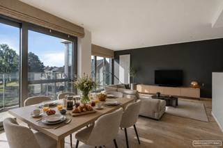 Op zoek naar een instapklaar appartement waar ruimte, comfort en een rustige ligging hand in hand gaan? Dan is dit stijlvolle 3-slaapkamerappartement in het centrum van Anzegem zeker een bezoek waard. Je geniet er van een aangename woonomgeving met uitzicht op het groen, terwijl scholen, sportfaciliteiten, supermarkten, bakkers en horeca zich op wandelafstand bevinden. Bovendien bereik je vlot de E17 en Waregem.
<h3>Indeling van het appartement</h3>
Via de <strong>inkomhal</strong>, uitgerust met een praktische ingebouwde <strong>vestiairekast</strong>, kom je binnen in de <strong>lichtrijke leefruimte</strong>. Een elegante glazen deur scheidt de inkom van de woonruimte en zorgt voor een open, moderne uitstraling. De leefruimte sluit naadloos aan op de <strong>volledig uitgeruste keuken met eeteiland</strong>, oven, kookplaat, plaats voor een microgolfoven en koelkast. Achter de keuken bevindt zich een handige <strong>berging</strong> die extra opbergruimte biedt.<br /><br />Vanuit de leefruimte stap je het <strong>ruime terras </strong>op, waar je in alle rust geniet van een prachtig zicht op het omliggende groen. Het volledige appartement is bovendien uitgerust met <strong>automatische screens</strong>, wat zorgt voor extra comfort en privacy.<br /><br />Het appartement beschikt over <strong>drie volwaardige slaapkamers</strong>. Slaapkamers één en twee geven rechtstreeks uit op het <strong>achterliggende terras</strong>, waar zich ook een <strong>praktische buitenberging</strong> bevindt. De stijlvolle <strong>badkamer</strong> is voorzien van een <strong>dubbel lavabomeubel, een ruime inloopdouche en ingebouwde kasten</strong>. <strong>De derde slaapkamer beschikt over een eigen dressing en aansluitingen voor een wasmachine en droogkas</strong>t.<br /><br />De residentie is kleinschalig en biedt een aangename woonomgeving. <strong>Vooraan het gebouw </strong>bevindt zich <strong>een gezellig parkje met petanquebaan en enkele zitbanken</strong>, ideaal om even te ontspannen. Daarnaast zijn er <strong>bezoekersparkeerplaatsen</strong>, een <strong>fietsenrek én een gemeenschappelijke afvalberging,</strong> wat het dagelijks comfort extra verhoogt.<br /><br />Een <strong>garage</strong> kan optioneel worden aangekocht voor <strong>€ 25.000</strong>.
<h3>Troeven</h3>
<ul>
<li>Instapklaar 3-slaapkamerappartement</li>
<li>Aankoop onder registratierechten (2% of 12%)</li>
<li>Rustig gelegen met zicht op het groen</li>
<li>Lichtrijke leefruimte met moderne keuken en eeteiland</li>
<li>Automatische screens in het volledige appartement</li>
<li>Twee terrassen, inclusief buitenberging</li>
<li>Derde slaapkamer met dressing en wasvoorzieningen</li>
<li>Kleinschalige residentie</li>
<li>Bezoekersparking, fietsenrek en gemeenschappelijke afvalberging</li>
<li>Vlotte verbinding naar Anzegem centrum, Waregem en de E17</li>
<li>Garage afzonderlijk aan te kopen (€ 25.000)</li>
</ul>
<h3>Bezoekmoment 13 juli</h3>
Interesse? Schrijf je in voor het bezoekmoment op maandag 13 juli vanaf 15 uur via de zwarte knop 'Maak nu een afspraak' op onze website.<br />Heb je nog vragen? Sarah helpt je graag verder via sarah@maesconceptimmo.be.