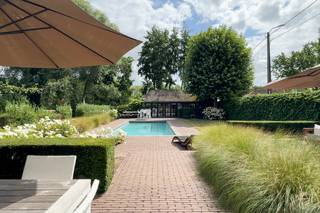 Sommige woningen moet je binnenstappen om te begrijpen. Deze is er zo één.<br /><br />Achter de met wingerd begroeide gevel van Spaans Fort 16 gaat een huis schuil dat authentieke charme moeiteloos verzoent met hedendaags comfort. Volledig gerenoveerd met oog voor detail, waarbij massieve materialen, warme haarden en kwalitatieve technieken samen één geheel vormen.<br /><br />Je komt binnen in een woning die meteen omarmt. Twee ruime, doorlopende leefruimtes liggen op een prachtige massieve eiken vloer, met tussenin een op maat gemaakte houten schuifdeur als karaktervol accent. Twee sfeerhaarden zorgen voor die onmiskenbare gezelligheid — en met in totaal vier haarden, gietijzeren radiatoren en authentieke terracotta in de eetkamer ademt elk hoekje warmte en klasse. Een groot schuifraam brengt de tuin naar binnen.<br /><br />De keuken, hoogwaardig uitgerust met onder meer een Lacanche-fornuis en natuurstenen werkblad, sluit naadloos aan op de eetkamer. Boven vind je een riante slaapkamer, een tweede slaapkamer met inloopkast, en een verzorgde badkamer met ligbad, dubbele wastafel en inloopdouche.<br /><br />Buiten wordt het pas echt genieten. Het verwarmde zwembad van circa 4 x 9,5 meter, met automatisch rolluik en recent vernieuwde technieken, vormt het kloppende hart van een klassevol aangelegde tuin met twee terrassen. Het volledig omgebouwde bijgebouw (ca 35 m2) met keuken, douche, zithoek en technische berging belooft urenlange feesten en zwoele zomeravonden.<br /><br />En het comfort zit ook in de cijfers: EPC-label B, conforme elektrische keuring, een nieuwe condensatieketel (2024) met boiler, ontkalker, 10 zonnepanelen en dakisolatie. De warmtepomp voor het zwembad werd geplaatst in 2010. De zwembadpomp werd vernieuwd in 2025 en de zandfilter in 2021. Daarnaast werd het zwembad ongeveer vier à vijf jaar geleden volledig opnieuw gepolyesterd, waardoor het technisch in perfecte staat verkeert. Parkeren doe je moeiteloos voor de deur en aan het bijgebouw.<br /><br />Authentiek wonen, vakantiegevoel het hele jaar door, op een steenworp van Antwerpen. Of je het bekijkt als een gezinswoning, luxe B&B of buitenverblijf, dit unieke huis laat zich niet samenvatten, enkel ontdekken.<br /><br />Alle attesten en plannen zijn te raadplegen op onze website bij documenten. <br /><br /><strong>Voor meer informatie (www.wellimmo.net ) of een bezichtiging mail info@wellimmo.net of tel 03 225 00 68.</strong><br /><br /><br />