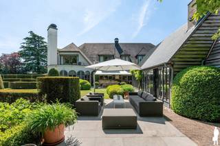 Unieke villa met binnenzwembad, vijver, polyvalente ruimte en garage op 15.399m² te Lier/Koningshooikt. <br /><br />Algemeen:<br />- Mooie villa met binnenzwembad<br />- Gelegen op een prachtig perceel van 15.399 m²<br />- Achtergelegen polyvalente ruimte (ca. 315m²)<br />- Achtergelegen garage/magazijn met aparte ingang (ca. 611 m²)<br />- Conciërgewoning (ca. 105m²) boven polyvalente ruimte<br />- Grote vijver<br />- Woning is deels verbouwd in 2006<br />- Keuken vernieuwd in 2021<br />- Nieuw dak op bijgebouw in 2024<br />- Top EPC score: 120 kWh/m²/jaar (label B)<br />- 102 zonnepanelen op het magazijn<br />- Prachtige orangerie met bbq/haard<br /><br />Indeling:<br />De kwalitatieve villa gelegen met grote leefruimte, eetkamer, keuken, binnenzwembad, bar, sauna, grote tuinkamer/orangerie,... Deze villa beschikt over een mooi aangelegde tuin met grote vijver. Op de eerste verdieping van de woning zijn 5 slaapkamers en 3 badkamers gelegen. In de slaapkamers is bovendien ook airco aanwezig. <br /><br />Daarnaast is er een verbinding op het gelijkvloers tussen de woning en de polyvalente ruimte en het magazijn. Achteraan is een groot magazijn/garage aanwezig, deze is toegankelijk via een poort en een aparte in- en uitrit aan de straatkant.<br />Boven de polyvalente ruimte is een conciërgewoning van ca. 105 m² met 2 slk, badkamer, leefruimte met open keuken en terrasje.<br /><br />Voor de exacte indeling bekijk de plannen op onze website.