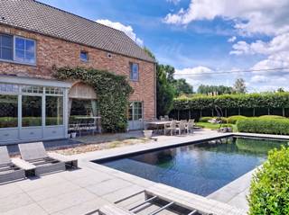<p>Met trots stellen wij u deze uitzonderlijke villa voor, gelegen in het groene Begijnendijk! Deze instapklare eigendom combineert ruimte, comfort en energiezuinigheid op een perceel van maar liefst 1.070 m², met een bewoonbare oppervlakte van ca 370 m².<br />Bij het betreden van de woning wordt u verwelkomd in een ruime L-vormige leefruimte waar grote raampartijen een prachtig zicht bieden op de tuin met zwembad. De hoogwaardige afwerking en het gevoel van openheid zorgen hier voor een aangename woonbeleving. Aansluitend bevindt zich de volledig uitgeruste keuken voorzien van een Falcon fornuis, ideaal voor kookliefhebbers. Verder beschikt het gelijkvloers over een praktische berging/wasplaats en een dubbele garage.<br />Op de eerste verdieping vindt u een luxueuze badkamer uitgerust met bubbelbad en een ruime inloopdouche. Daarnaast zijn er vijf volwaardige slaapkamers en een dressing.<br />De tweede verdieping biedt een bijzonder ruime extra slaapkamer met reeds aanwezige watervoorziening. Dit biedt tal van mogelijkheden.<br />De fraai aangelegde tuin vormt een echte oase van rust. Hier geniet u van het zwembad en het volledige ingerichte poolhouse. De ideale setting voor ontspanning en gezellige momenten samen.<br />Deze energiezuinige villa beschikt over 24 zonnepanelen en behaalt een EPC-score B, wat bijdraagt aan een duurzame en toekomstgerichte woonervaring.</p><p>Interesse? Contacteer ons voor een bezoek en laat u charmeren door deze prachtige villa.<br />EPC: 111 kWh/m² UC: 20260407-0003842368-RES-2<br /> </p>