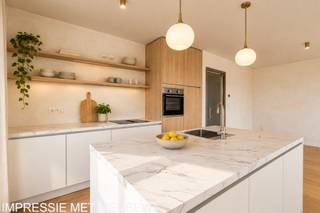 <p><strong>Residentie Tamboer – uw eigen ritme, midden in Turnhout</strong><br />De dag begint met licht dat langs twee kanten de leefruimte binnenvalt. U drinkt koffie met zicht op de stad, wandelt later naar de Grote Markt en komt ’s avonds thuis op een terras waar de laatste zon nog blijft hangen. Dat is het leven in dit penthouse van Residentie Tamboer: de stad dichtbij, met thuis alle ruimte om tot rust te komen.</p>
<p>De residentie dankt haar naam aan de tamboer, de trommelaar die het ritme aangeeft en de stoet voorgaat. Ook hier draait alles om ritme: de levendigheid van Turnhout wanneer u die opzoekt, en de rust van uw eigen plek wanneer u thuiskomt. Net binnen de ring woont u bij water, groen en wandelpaden, met de Grote Markt en het Stadspark op wandelafstand.</p>
<p><strong>Een terras dat mee leeft met uw dag</strong><br />Dit appartement biedt 114 m² bewoonbare oppervlakte en maar liefst 61 m² aan zuid en west georiënteerde terrassen. Het terras loopt rond het appartement en biedt plaats aan meerdere zithoeken: een tafel om buiten te eten, een plek om te lezen, of allebei. Dankzij de zuid en westelijke oriëntatie geniet u van de zon op elk moment van de dag. Tegelijkertijd biedt het overdekt terras schaduw wanneer u daar behoefte aan heeft.</p>
<p>Binnen vormen de zithoek, eetruimte en stijlvolle keuken één open leefruimte. In de leefruimte is er een aangename bureauhoek. Grote ramen brengen aan twee zijden daglicht binnen en verbinden het interieur met het terras. De lichte eiken parketvloer geeft de leefruimtes een warme, tijdloze uitstraling.</p>
<p>Ook de drie slaapkamers hebben toegang tot de terrassen. De hoofdslaapkamer beschikt over een eigen badkamer. Voor de twee andere kamers is er een aparte douchekamer. Richt ze in als slaapkamers, bureau, dressing of hobbyruimte: de indeling geeft u de vrijheid om het appartement aan uw leven aan te passen.</p>
<p><strong>Groot in mogelijkheden, aangenaam in schaal<br /></strong>Residentie Tamboer combineert eigentijdse architectuur met warme materialen en groene gevels. De residentie is opgedeeld in compartimenten met elk een eigen trap en lift. Zo maakt u deel uit van een groter woonproject, terwijl u de gemeenschappelijke delen met slechts een beperkt aantal andere appartementen deelt.</p>
<p>Op het gelijkvloers is een ruime fietsenstalling voorzien. Uw wagen parkeert u in de afgesloten parkeerkelder.</p>
<p>De vraagprijs van dit appartement bedraagt € 409.400 exclusief kosten. Parkeerplaatsen zijn verkrijgbaar vanaf € 20.900 en bergingen vanaf € 4.500. Inclusief btw, registratierechten, notariskosten, één parkeerplaats en één berging bedraagt de totale aankoopprijs circa € 528.000.</p>
<p>Achter Residentie Tamboer staat DC Belgium, een ervaren Belgische projectontwikkelaar met aandacht voor woonkwaliteit en groen. Van uw eerste kennismaking tot de afwerking van uw appartement wordt u persoonlijk begeleid.</p>