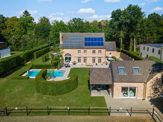 <p><strong>Exclusieve villa met tweede woonentiteit, paardenaccommodatie en infinity pool aan Rinkven Golf</strong></p>
<p><strong>Uitzonderlijk gerenoveerde villa met multifunctioneel bijgebouw, paardenaccommodatie, verwarmd infinityzwembad en schitterende uitrijmogelijkheden, gelegen op een uniek perceel van ca. 5.000 m² aan de golf van Rinkven in Sint-Job-in-'t-Goor.</strong></p>
<p>Op een absolute toplocatie, rechtstreeks grenzend aan de prestigieuze golf van Rinkven, bevindt zich deze royale en energiezuinige villa met een uitzonderlijk aanbod aan woon- en ontspanningsfaciliteiten. Het geheel omvat naast de hoogwaardig afgewerkte hoofdwoning ook een volwaardige tweede woonentiteit – momenteel ingericht als schoonheidssalon – een verwarmd infinityzwembad, paardenstallen en een rijbak met uitstekende uitrijmogelijkheden.</p>
<p>De villa werd oorspronkelijk gebouwd in 2000 en in 2020 volledig en bijzonder grondig gerenoveerd. Daarbij werd niet alleen aandacht besteed aan esthetiek en wooncomfort, maar eveneens aan energiezuinigheid, hedendaagse technieken en hoogwaardige afwerking.<br /><br /></p>
<p><strong>Hoofdwoning</strong></p>
<p><strong>Gelijkvloers</strong></p>
<p>De royale inkomhal vormt een stijlvolle entree en geeft toegang tot de verschillende leefruimtes en de verdieping. Hier bevinden zich tevens een vestiaire, gastentoilet en afzonderlijk bureel.</p>
<p>De bijzonder ruime leefruimte is ingedeeld in verschillende sfeervolle zones, waaronder een elegante eethoek, een comfortabele zitkamer met doorkijk-gashaard en een uitnodigende lounge. Grote raampartijen zorgen voor een aangename lichtinval en versterken de verbinding met de omliggende tuin en het unieke uitzicht.</p>
<p>De luxueuze maatwerkkeuken is uitgerust met hoogwaardige apparatuur en beschikt over een strak en eigentijds ontwerp met geïntegreerde, vrijwel onzichtbare kookpitten.</p>
<p>Verder omvat het gelijkvloers een praktische wasplaats en koele berging, evenals toegang tot de ruime dubbele inpandige garage. De verdieping van de garage is momenteel ingericht als gameroom/fitnessruimte en biedt tal van mogelijkheden voor verdere invulling.</p>
<p><strong>Eerste verdieping</strong></p>
<p>De eerste verdieping beschikt over drie ruime slaapkamers, waarvan momenteel één kamer stijlvol is ingericht als dressing.</p>
<p>Er is een aparte badkamer met douche en maatwerkmeubel.</p>
<p>De royale master suite vormt een volwaardige privéverdieping binnen de woning en beschikt over een ruime dressing en een luxueuze badkamer, uitgerust met een ruime inloopdouche en ligbad.</p>
<p><strong>Zolderverdieping</strong></p>
<p>Via een vaste trap is de ruime zolder bereikbaar. Dankzij de beschikbare oppervlakte en indeling kunnen hier relatief eenvoudig nog <strong>twee bijkomende slaapkamers en een badkamer</strong> worden gerealiseerd.<br /><br /></p>
<p><strong>Multifunctioneel bijgebouw – volwaardige tweede woonentiteit</strong></p>
<p>Het bijgebouw is momenteel ingericht als schoonheidssalon, maar heeft dankzij zijn volwaardige voorzieningen en zelfstandige indeling eveneens de potentie om als tweede woning, gastenverblijf, kantoor of praktijkruimte te worden gebruikt.</p>
<p>Deze tweede woonentiteit maakt het eigendom bijzonder veelzijdig en biedt interessante mogelijkheden voor <strong>dubbele bewoning, inwonende familie, gasten, een zelfstandige activiteit of professionele doeleinden</strong>.</p>
<p><strong>Buitenbeleving & paardenaccommodatie</strong></p>
<p>De tuin is ingericht rond een <strong>verwarmd infinityzwembad met overlooprand en buitendouche</strong>, waardoor een bijzonder aangename vakantiesfeer ontstaat.</p>
<p>Voor paardenliefhebbers is de eigendom uitgerust met <strong>paardenstallen en een rijbak</strong>, gecombineerd met uitstekende mogelijkheden om rechtstreeks vanuit het perceel uit te rijden.</p>
<p>De ligging aan de golf van Rinkven vormt bovendien een uniek decor en zorgt voor een bijzonder open en groen karakter.</p>