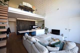 Dit lichtrijke duplex appartement is ideaal gelegen op wandelafstand van het centrum van Gent en biedt een aangename combinatie van ruimte en comfort.<br /><br />Bij het betreden van het appartement komt u terecht in een lichtrijke leefruimte met grote raampartijen en een open, volledig uitgeruste keuken. De moderne keuken is afgewerkt met kwalitatieve toestellen en biedt bovendien een praktische berging. Op deze verdieping bevindt zich eveneens een gastentoilet, een eerste slaapkamer en een bijzonder ruim en zonnig terras, waar het heerlijk vertoeven is in alle rust.<br /><br />De bovenverdieping straalt luxe en functionaliteit uit. De mezzanine vormt de perfecte plek voor een bureau of creatieve werkruimte. De recent (2025) volledig vernieuwde badkamer is stijlvol ingericht met een inloopdouche en dubbele lavabo. Daarnaast vindt u een nachthal met ingemaakte kasten, een tweede toilet, een dressing, een tweede volwaardige slaapkamer en een aparte berging met aansluiting voor wasmachine en droogkast.<br /><br />Het appartement beschikt bovendien over een privatieve kelderberging en biedt de mogelijkheid om een ondergrondse parkeerplaats bij te huren aan €100 per maand.<br /><br />•Beschikbaar vanaf 01/08/2026 <br />•Algemene kosten: €150/maand <br />•Individuele tellers voor elektriciteit, gas en water<br /><br />EPC A - 20260429-0003858898-RES-1