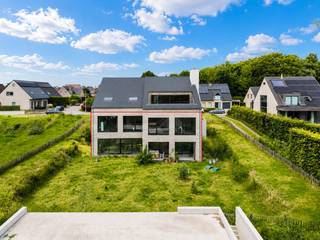 Deze casco woning biedt een uitzonderlijke kans om een unieke woonst volledig naar eigen smaak en wensen af te werken. De hoge plafonds en de grote verscheidenheid aan raampartijen zorgen voor een bijzonder open ruimtegevoel en een overvloed aan natuurlijke lichtinval. Het geheel is geen klassieke woning, maar een gedurfd architecturaal ontwerp met een uitgesproken karakter.<br /><br />Bij het betreden van de woning via de voordeur, gelegen uiterst links van het gebouw, komt u op de verdieping op straatniveau. Hier bevinden zich momenteel twee ruime slaapkamers, die eenvoudig kunnen worden opgesplitst tot vier slaapkamers, met vanuit de hal reeds de nodige deuropeningen. In elke kamer kan bovendien een kleine badkamer worden ingericht. In de hal is er mogelijkheid voor een afzonderlijk toilet en een lift. <br /><br />Daarnaast is er een bijzonder ruime multifunctionele ruimte aanwezig, die eveneens toegankelijk is via een afzonderlijke inkomdeur aan de rechterzijde van de woning. Deze ruimte is uitermate geschikt voor een vrij beroep of zelfstandige activiteit aan huis.<br /><br />Via de architecturale trap bereikt u de lager gelegen verdieping, waar zich het leefgedeelte bevindt. Hier vindt u een ruime en lichtrijke leefruimte met mogelijkheid voor een open keuken, aansluitende berging en eetplaats. Daarnaast is er nog een extra multifunctionele ruimte die kan worden ingericht als master bedroom met aansluitende badkamer en sauna, wellnessruimte, hobbykamer of bureau.<br /><br />Deze verdieping is eveneens rechtstreeks toegankelijk via een zijdelingse inkomdeur, wat een vlotte verbinding met de afzonderlijke garage mogelijk maakt. Aan deze inkom is mogelijkheid voor een vestiaire, een afzonderlijk toilet en een praktische wasruimte.<br /><br />De woning wordt casco aangeboden, waardoor zowel de indeling als de afwerking nog volledig vrij te bepalen zijn. Dit biedt een unieke opportuniteit om een woning te creëren die volledig aansluit bij uw eigen levensstijl.<br /><br />Voorstudie EPB resulteert in een E-peil van 20. <br /><br />Op de bovenste verdieping is een bijkomende wooneenheid voorzien, toegankelijk via een afzonderlijke inkom in het midden van de woning. Deze unit wordt eveneens casco aangeboden en kan afzonderlijk worden aangekocht, maar de aankoop van het geheel is uiteraard ook mogelijk.