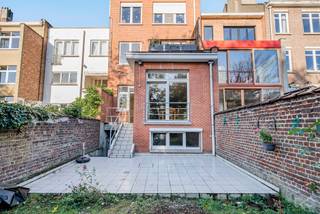 Gelegen in een rustige en residentiële wijk biedt dit gelijkvloers appartement met een oppervlakte van ongeveer 89 m² een aangename en comfortabele woonomgeving. Het bestaat uit een inkomhal, een ruime en lichte woon- en eetkamer, evenals een volledig uitgeruste keuken. Het appartement beschikt momenteel over één slaapkamer, maar een grote ruimte met toegang tot de tuin maakt het mogelijk om eenvoudig een tweede slaapkamer te creëren indien gewenst. Verder is er een douchekamer en een kelder aanwezig. Buiten vindt u een groot terras en een privétuin, ideaal om van zonnige dagen te genieten. Het pand is voorzien van een veiligheidsdeur, dubbele beglazing en nieuwe rolluiken aan alle ramen. Gelegen in een klein gebouw met lage lasten combineert dit appartement comfort, rust en nabijheid van winkels, openbaar vervoer en andere voorzieningen. Zeker een bezoek waard.