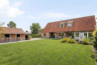 Luxueuze villa met paardenaccomodatie, in een groene, landelijke omgeving. Op een prachtige rustige locatie bevindt zich deze uitzonderlijke villa, opgetrokken in een stijlvolle landelijke architectuur en afgewerkt met hoogwaardige materialen. Deze eigendom combineert charme, comfort en kwaliteit en biedt een unieke woonbeleving voor wie houdt van ruimte, rust en een verfijnde levensstijl.Bij het betreden van de woning valt meteen de aandacht voor detail op. De natuurstenen vloeren, keukenbladen in hoogwaardige materialen en het volledig uitgevoerde binnenschrijnwerk in volle eik getuigen van een tijdloze elegantie. Het buitenschrijnwerk in tropisch hardhout onderstreept de duurzame en kwalitatieve afwerking van deze prachtige villa.De woning beschikt over ruime en lichtrijke leefruimtes, ideaal voor zowel dagelijks comfort als het ontvangen van gasten. Met 5 slaapkamers en 2 badkamers biedt de villa alle ruimte voor een gezin of wie extra kamers wenst voor kantoor, hobby of logies. Op het gelijkvloers bevindt zich een bijzonder comfortabele mastersuite met dressing en aansluitende badkamer.Buiten geniet u van een prachtig aangelegde tuin met sfeervolle waterpartij, die naadloos aansluit op de omliggende weide. De aanwezigheid van paarden- of ponystallingen maakt deze eigendom bijzonder aantrekkelijk voor paardenliefhebbers of wie droomt van een landelijke levensstijl.Daarnaast beschikt de woning over een ruime carport voor 3 wagens en tal van praktische voorzieningen.Een uitzonderlijke eigendom, perfect onderhouden tot in de kleinste details, waar kwaliteit, ruimte en landelijke charme harmonieus samenkomen.