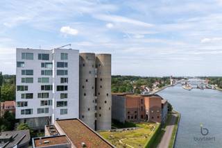 <p><span>BEKIJK OOK ONS FILMPJE! Klik hierboven op het 'scherm-icoontje'! </span></p><p><span>Wonen op een uitzonderlijke locatie met panoramisch uitzicht: exclusief appartement in de iconische Silo's!</span></p><p><span>Het Project Kanaal van Axel Vervoordt is een unieke bestemming waar wonen, kunst, architectuur en gastronomie samenkomen. Omgeven door water, groen en indrukwekkende industriële erfgoedarchitectuur geniet u hier dagelijks van rust, ruimte en een inspirerende leefomgeving. Authentieke elementen, tijdloze architectuur en duurzame materialen vormen samen een unieke leefomgeving waar karakter, comfort en esthetiek perfect in balans zijn. Dankzij de strategische ligging in Wijnegem, vlak bij Schilde en Antwerpen, combineert deze unieke locatie het beste van twee werelden: een rustige, groene woonomgeving met alle voorzieningen en uitvalswegen in de onmiddellijke nabijheid.</span></p><p><span>Gelegen op de vierde verdieping van de Silo's geniet dit exclusieve appartement van ca. 202 m² van een panoramisch uitzicht over het Albertkanaal en het prachtig aangelegde domein. Het interieur werd ontworpen door binnenhuisarchitect Marc Lauwers en combineert tijdloze elegantie met uitzonderlijk wooncomfort.</span></p><p><span>De unieke indeling bestaat uit drie cirkelvormige ruimtes met elkaar verbonden door middel van kleine glazen bruggen en een transparant vierkant volume. Bij het binnenkomen treft u een sfeervolle bibliotheekruimte, een gastentoilet en een polyvalente kamer die dienst kan doen als logeer-, hobby- of bureauruimte.</span></p><p><span>Het hart van het appartement wordt gevormd door de indrukwekkende leefruimte met open keuken en eetgedeelte. Dankzij de grote glaspartijen aan drie zijden baadt deze ruimte de hele dag in natuurlijk licht en geniet u van een voortdurend contact met de omgeving. De hoogwaardige keuken werd sober en stijlvol vormgegeven met zeer kwalitatieve materialen en toestellen.</span></p><p><span>De tweede cirkelvormige ruimte herbergt een royale zithoek met centrale gashaard, waar de gebogen architectuur zorgt voor een warme en rustgevende sfeer.</span></p><p><span>De master suite beschikt over maatwerkkasten en een luxueuze badkamer uitgerust met een dubbel lavabomeubel, ligbad, inloopdouche en afzonderlijk toilet. De westelijke oriëntatie zorgt hier voor een aangename avondzon.</span></p><p><span>Een ondergrondse autostaanplaats is bijkomend aan te kopen voor +30.000€. Verder beschikt u over 2 eigen fietsenplaatsen en gebruiksrecht van de tuin.</span></p><p><span>Bijzonderheden: high-end afwerking, EPC-label A, ventilatiesysteem D, panoramische zichten en een unieke architecturale woonbeleving.</span></p><p><span>Maandelijkse gemeenschappelijke kosten: ca. 300€</span></p><p><span>Contacteer ons voor meer informatie of een bezoek!</span></p><p><span> </span></p><p><span> </span></p>