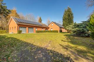 Kijkmoment op vrijdag 19 juni - graag telefonisch bevestigen via 03 289 11 00.<br /><br />Deze vrijstaande woning ligt op een centrale locatie in Tremelo, omgeven door groen. Via een mooie oprijlaan kom je uit aan de achtergelegen open bebouwing, gelegen op een perceel van ca. 3400m². Met de nabijheid van het centrum, van vlotte verbindingen naar Mechelen, Leuven of andere invalswegen én tal van wandel- en fietsmogelijkheden in de streek, is de ligging van dit pand een grote troef. De streek staat bekend om haar rustige karakter en mooie natuur.<br /><br />De woning beschikt over een ruime gelijkvloerse indeling, met inkomhal, een lichtrijke woon- en eetkamer, een keuken met aansluitend een veranda, een apart toilet, een douchekamer, een bergruimte, een masterbedroom met ensuite badkamer en nog 2 volwaardige slaapkamers. De bovenverdieping bestaat uit nog eens 3 slaapkamers en een zéér grote zolderverdieping met potentieel tot extra kamers. Verder zijn er 3 garages en zeer veel atelier- en bergruimte.<br /><br />Troeven: prachtige groene ligging - veel mogelijkheden qua indeling - zonnepanelen - 6 volwaardige slaapkamers - ruimte voor het parkeren van meerdere wagens - belangrijkste ruimtes op de gelijkvloerse verdieping, wat potentieel biedt voor woon-werk combinatie of kangoeroe woning.