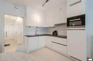 Elegant 1 slaapkamer appartement in recent gebouw.# Indeling en RuimteHet appartement beschikt over een geïntegreerde woonkamer met slaapgedeelte, waarbij de ruimte optimaal is benut. De open indeling zorgt voor een licht en uitnodigend interieur. De voorkamer biedt voldoende ruimte voor zowel zithoek als slaaparea, perfect voor wie efficiënt willen wonen zonder concessies te doen aan comfort.# KeukenDe moderne, volledig ingerichte woonkeuken is voorzien van kwalitatieve apparatuur waaronder een inbouwoven en magnetron. Het compacte formaat is praktisch vormgegeven met voldoende bergruimte. De keuken beschikt over een werkblad met spoelbak en is afgewerkt met neutrale tegels voor eenvoudig onderhoud.# BadkamerDe eigentijdse badkamer is voorzien van een douchecabine met glazen wanden, een houten wastafel met spiegel en moderne sanitair. Dit zorgvuldig ontworpen ruimte combineert functionaliteit met stijl.# Terras en BuitenruimteEen absolute highlight is het ruime privéterras met houten dekking. Dit buitenruimte biedt de perfecte plek om van frisse lucht te genieten en voorziet in die gewenste outdoor-living ervaring.# Afwerking en DetailsHet appartement is afgewerkt met lichte neutrale kleuren en hoogwaardige materialen. Plinten, LED-verlichting en moderne voorzieningen dragen bij aan het gerenoveerde karakter. De ruimtes beschikken over voldoende natuurlicht door doordachte raamplaatsing.Als extra troef is het mogelijk om voor een meerprijs van 45.000 euro een staanplaats te kopen in het gebouw.