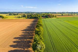 Te midden van een prachtig groen domein van ca. 3 hectare, bereikbaar via een lange private dreef, bevindt zich deze authentieke rustieke vierkantshoeve met uitzonderlijk veel charme en potentieel. De eigendom geniet van volledige rust en privacy, omringd door groene vergezichten, een eigen bos en een idyllische vijver die samen zorgen voor een uniek en sfeervol kader.<br /><br />Deze karaktervolle hoeve vormt de ideale plek voor wie op zoek is naar landelijk wonen met ruimte, authenticiteit en tal van mogelijkheden. Dankzij de combinatie van wooncomfort, royale bijgebouwen en het uitgestrekte perceel leent het geheel zich perfect voor paardenliefhebbers of een combinatie wonen-werken.<br /><br />Het woonhuis is functioneel ingedeeld en beschikt op het gelijkvloers over een inkomhal, gastentoilet, technische ruimte, keuken met eetplaats en een gezellige leefruimte met zicht op het omliggende groen. Op de eerste verdieping bevinden zich vier volwaardige slaapkamers en twee badkamers. De tweede verdieping biedt bijkomende mogelijkheden dankzij de ruime zolderverdieping.<br /><br />Verder beschikt het domein over een imposante schuur met authentieke eiken balkenstructuur, diverse opslagruimtes en paardenstallen. De charmante binnenkoer vormt het hart van de hoeve en versterkt het unieke karakter van deze eigendom.<br /><br />Een uitzonderlijke opportuniteit voor wie droomt van een karaktervolle hoeve op een absolute toplocatie in alle rust en natuur.