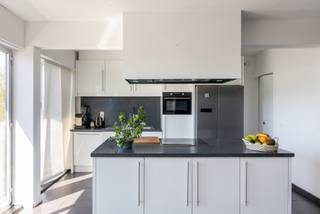 Locatie
Dit lichtrijke en goed onderhouden appartement is gelegen in Boechout, op wandelafstand van tal van winkels, supermarkten en andere voorzieningen langs de grote baan. Dankzij de vlotte bereikbaarheid en centrale ligging geniet u hier van optimaal wooncomfort.
Indeling
Bij het betreden van het appartement komt u in de inkomhal met ingebouwde kast en een apart gastentoilet. Daarnaast bevindt zich een ruime berging/bureau met aansluiting voor was- en droogmachine.
De gezellige, lichtrijke woonkamer met moderne open keuken vormt het hart van de woning en biedt directe toegang tot het eerste zonnige terras.
De badkamer is uitgerust met een ligbad en dubbele wastafel. Achteraan bevinden zich twee volwaardige slaapkamers, waarvan één met rechtstreekse toegang tot een tweede terras.
Momenteel is het appartement gunstig verhuurd aan een fijn gezin, wat het ook interessant maakt als investering.
Een garagebox is apart aan te kopen voor €25.000.
Troeven
- Centrale ligging nabij winkels en voorzieningen
- Twee zonnige terrassen
- Twee volwaardige slaapkamers
- Interessant als investering
- Garagebox (apart aan te kopen)
Technische gegevens
Lage gemeenschappelijke kosten en gunstig EPC-label B.