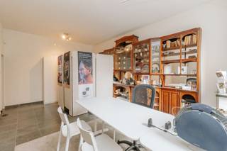 <p>In het geliefde Wilrijk, één van de meest gegeerde residentiële districten van Antwerpen, bevindt zich deze uitzonderlijke architecturale halfopen bebouwing, waar ruimte, licht en functionaliteit tot in de puntjes zijn uitgewerkt. Een unieke eigendom die wonen en werken op een bijzonder elegante manier verenigt.</p><p><br /></p><p>Bij het betreden van de woning kom je in een stijlvolle inkomhal. Aan de linkerzijde bevindt zich een volledig geïntegreerde praktijk- of kantoorruimte met eigen wachtzaal en apart toilet, discreet afgescheiden van het privéleven en ideaal voor vrije beroepen. Het woongedeelte verwelkomt je met een royale inkomhal en een vaste natuurstenen trap als architecturale blikvanger. Verder zijn er een vestiaire met gastentoilet en toegang tot de leefruimtes.</p><p>De lichtrijke keuken kijkt uit op de tuin en sluit naadloos aan op het leefgedeelte. Twee eetruimtes — een intieme plek en een ruimer eetgedeelte in het verlengde van de woonkamer — zorgen voor flexibiliteit en gezelligheid. Hoogwaardige materialen zoals de warme parketvloer en een strak ingebouwde zitbank geven de woning een moderne, verfijnde uitstraling.</p><p><br /></p><p>Op de bovenverdieping bevinden zich zes slaapkamers, waaronder een ruime master bedroom met aansluitende badkamer die ook toegankelijk is vanuit de gastenkamer. Daarnaast zijn er meerdere kamers die perfect kunnen dienen als bureau-, hobby- of slaapkamers. Achteraan bevindt zich een apart gedeelte met twee bijkomende slaapkamers en een badkamer, ideaal als gastenverblijf, tienerzone of extra werkruimte.</p><p><br /></p><p>De gezellige en private tuin vormt een verlengde van de woonruimtes en is deels aangelegd in stijlvol Meranti hout, wat zorgt voor een warme en luxueuze buitenbeleving. Verder beschikt de woning over een garage voor twee wagens, extra parkeergelegenheid op de oprit en een aparte fietsenstalling. Een zeldzame opportuniteit in Wilrijk voor wie op zoek is naar architecturale klasse, ruimte en een veelzijdige invulling.</p>