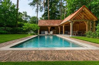 Welkom in deze uitzonderlijke villa, gelegen in een rustige en residentiële dreef in één van de meest gegeerde woonomgevingen van Heide-Kalmthout. Omringd door statige villa's op ruime percelen en volwassen bomen geniet u hier van absolute rust, privacy en een unieke woonkwaliteit.<br /><br />Ondanks de groene ligging bevinden de centra van Heide en Kapellenbos, scholen, winkels en openbaar vervoer zich op korte afstand. Dankzij de nabijheid van meerdere treinstations en de vlotte verbinding richting Antwerpen (en de haven) en Nederland combineert deze locatie moeiteloos exclusief wonen met een uitstekende bereikbaarheid. Ook natuurliefhebbers komen hier volledig aan hun trekken, met de Kalmthoutse Heide en de Golf van Kapellen vlakbij.<br /><br />Indeling van de villa:<br />Via de imposante inkomhal met open vide, vestiaire en gastentoilet wordt u verwelkomd in een woning waar ruimte, licht en luxe centraal staan.<br />De royale leefruimte bestaat uit een sfeervol salon met open haard en een aparte tv-kamer. De exclusieve leefkeuken vormt het hart van de woning en is afgewerkt met een indrukwekkend kookeiland, een La Cornue gasfornuis, hoogwaardige natuursteen en alle denkbare toestellen. Een droom voor menig hobbykok. Aansluitend bevindt zich een stijlvolle eetkamer met haard. Vanuit vrijwel elke leefruimte geniet u van een prachtig zicht op de tuin en heeft u directe toegang tot de terrassen.<br /><br />Eerste verdieping:<br />Via een stijlvolle trap bereiken we de eerste verdieping, waar zich een volledig afsluitbare mastervleugel bevindt met een ruime slaapkamer, luxueuze ensuite dressing en een luxe badkamer met ligbad, inloopdouche, dubbele wastafel en toilet. Daarnaast zijn er nog twee ruime slaapkamers, waarvan één met dressing en de andere ingericht als hobbykamer. De tweede badkamer is even luxueus ingericht met dubbele douche, ligbad en badkamermeubel. Op deze verdieping bevindt zich een super handige wasruimte en een nachttoilet.<br /><br />Tweede verdieping:<br />De trap zet zich voort naar de overloop van deze verdieping en beschikt over nog eens drie ruime slaapkamers, waarvan twee voorzien zijn van nieuwe maatwerkkasten. Een derde badkamer is eveneens uitgerust met ligbad, badkamermeubel en toilet.<br /><br />Buitenruimte:<br />De volledig nieuw aangelegde tuin ademt exclusiviteit. Hier geniet u van een verwarmd zwembad waarvan de geautomatiseerde filterinstallatie recent werd vernieuwd, een nieuwe luxueus uitgeruste poolhouse met buitenbar, kleedkamer, toilet en buitendouche. Dankzij de putboring en automatische irrigatie blijft de tuin het hele jaar door perfect onderhouden. Genieten van rust en de tuin kan u op één van de terrassen.<br /><br />Parkeren:<br />De woning beschikt over een ruime dubbele garage met automatische poorten, voorzieningen voor een laadpunt, een zij-ingang en een vernieuwde oprit met parkeergelegenheid voor meerdere wagens. Buiten het perceel is er nog parkeergelegenheid voor de gasten.<br /><br />Troeven van de villa:<br />•Exclusieve villa in tijdloze Cotswold-architectuur <br />•Volledig gerenoveerd en gemoderniseerd (2019 & 2024) <br />•Verwarmd zwembad met nieuwe filterinstallatie en luxueuze poolhouse <br />•Exclusieve leefkeuken met La Cornue-fornuis <br />•Zes ruime slaapkamers en drie complete badkamers<br />•Afsluitbare mastervleugel met dressing en ensuite badkamer <br />•Zonnepanelen, waterverzachter en putboring <br />•Energiezuinig B-label <br />•Absolute privacy op een residentiële toplocatie <br /><br />Kortom:<br />Deze villa is een unieke opportuniteit voor wie op zoek is naar een luxueuze gezinswoning waar architectuur, comfort en natuur naadloos samensmelten. Elk detail werd met oog voor kwaliteit afgewerkt, waardoor u hier zonder zorgen kan genieten van exclusief wonen in één van de mooiste lanen van Heide-Kalmthout.<br /><br />Overtuig uzelf van deze unieke buitenkans tijdens een bezoek ter plaatse.