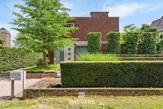 Voor meer info en foto’s, surf naar www.swevers.be – Deze ruime open bebouwing aan de Langerloweg 39 in Genk biedt een uitstekende combinatie van ruimte, ligging en mogelijkheden. Gelegen in een rustige woonomgeving op slechts 1,8 km van het centrum, geniet u hier van een vlotte bereikbaarheid met scholen, winkels, horeca, openbaar vervoer en de autosnelweg in de nabije omgeving. De woning werd gebouwd in 1969 en beschikt over een bewoonbare oppervlakte van 184 m² op een royaal perceel van 945 m². Dankzij vernieuwde ramen (2008) en een gerenoveerde badkamer (2009) zijn reeds belangrijke investeringen uitgevoerd. Binnen verwelkomt een ruime inkomhal u naar de lichtrijke woonkamer van circa 38 m², waar grote raampartijen zorgen voor een aangename sfeer en veel natuurlijk licht. De aansluitende keuken van ongeveer 14 m² biedt de mogelijkheid om een moderne leefkeuken te creëren met directe toegang tot terras en tuin. Op de verdieping bevinden zich vier slaapkamers, ideaal voor gezinnen of wie extra ruimte wenst voor een bureau of hobbykamer. De vernieuwde badkamer is uitgerust met een ruime douche en wastafel. Daarnaast is er een afzonderlijk toilet aanwezig. Een absolute troef is de volledige onderkeldering van 103 m², inclusief een inpandige garage van 44 m² met plaats voor twee wagens. Deze extra ruimte biedt tal van mogelijkheden voor opslag, hobby’s of werkruimte. Buiten geniet u van een verzorgde tuin met oostelijke oriëntatie, veel privacy en een aangename groene omgeving. Een ideale gezinswoning voor wie ruimte zoekt en deze verder naar eigen smaak wil moderniseren. <br /><br />Dit pand is onderworpen aan de renovatieverplichting van de Vlaamse overheid voor residentiële gebouwen (behoudens bij sloop binnen 5 jaar na de aankoop). Consulteer voor meer informatie de website van het Vlaams Energie- en Klimaatagentschap via https://www.vlaanderen.be/een-huis-of-appartement-kopen/renovatieverplichting-voor-residentiele-gebouwen.<br /><br />Voor meer informatie, bel 011 255 155. Bron bewoonbare oppervlakte: EPC – verslag.