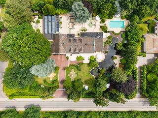Te midden van absolute rust, pal naast het prachtige Nationaal Park Hoge Kempen, bevindt zich deze uitzonderlijke residentie: “Manoir des Lions”. Een iconische luxevilla met een indrukwekkende bewoonbare oppervlakte van maar liefst 1.184 m², gelegen op een volledig privatief domein van 5.246 m².<br /><br />Deze exclusieve eigendom werd oorspronkelijk gebouwd in 1969 en onderging vanaf 2009 een totaalrenovatie met oog voor luxe, comfort en verfijning. Vandaag verkeert de villa in een uitmuntende staat van onderhoud en werd ze afgewerkt met hoogwaardige materialen en exclusieve designelementen, geïnspireerd door de stijlvolle signatuur van Pieter Porters.<br /><br />Indeling gelijkvloers:<br />Een statige inkomhal met vestiaire en gastentoilet leidt naar de royale leefruimtes, bestaande uit een stijlvolle woonkamer met eetgedeelte, tv-salon, bar en bureel. Daarnaast beschikt de villa over twee luxueus afgewerkte keukens met natuurstenen werkbladen en hoogwaardige toestellen, beide met directe toegang tot het verwarmde overdekte terras.<br /><br />Wellness & ontspanning:<br />Het absolute paradepaard van deze residentie is de exclusieve wellnessvleugel van ca. 413 m² met verwarmd binnenzwembad, sauna, fitnessruimte, stijlvolle lounge en bar, wijncorridor, ontspanningsruimte met biljart.<br />De grote raampartijen creëren een unieke connectie met de aangelegde tuin en zorgen voor een uitzonderlijke lichtinval.<br /><br />Verdiepingen:<br />Op de eerste verdieping bevinden zich twee ruime slaapkamers, waaronder één met privatieve dressing, een luxueuze badkamer en een royaal dakterras.<br />De tweede verdieping is volledig ingericht als exclusieve master suite met badkamer en suite en meerdere dressings.<br />De kelderverdieping biedt bijkomende bergruimte, archiefmogelijkheden en extra fitnessfaciliteiten.<br /><br />Buitenomgeving:<br />De prachtig aangelegde tuin vormt een waar privéresort met: Verwarmd buitenzwembad, elegant poolhouse, zwemvijver met fonteinen, meerdere terrassen en loungezones.<br /><br />Buitengewone kenmerken:<br />- Lift aanwezig<br />- Inpandige garage voor 3 voertuigen<br />- open haarden<br />- Camerabewaking en laserbeveiliging<br />- Geharde veiligheidsbeglazing<br />- Hoogwaardige afwerkingsgraad<br />- Zeer breed perceel<br />- Binnen- én buitenzwembad<br />- Absolute privacy en rust<br />- Twee afzonderlijke inritten.