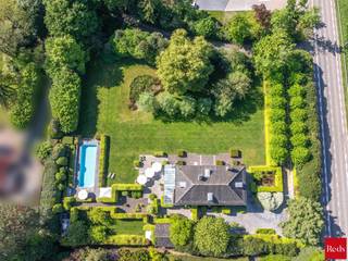 <p><strong>Met gepaste trots stellen wij u dit unieke pareltje voor, op een boogscheut van het centrum van Lier.</strong><br />Dit domein van 3.877 m² ligt uiterst landelijk en rustig, maar is tegelijk vlot bereikbaar via de E19. Zowel het stadscentrum als het Netelandschap bevinden zich op wandel- en fietsafstand.</p>
<p>De eigenaars kozen hier voor een prachtig, authentiek gebouw met hoogwaardige, natuurlijke bouwmaterialen zoals extra dikke eikenhouten vloeren, massieve houten maatwerkkasten en -deuren, en natuursteen. Met de schitterende orangerie, de fantastische tuin en het extra lange zwembad heerst hier een echt vakantiegevoel.</p>
<p>Een deel van het perceel is vergund verkaveld als bouwgrond, wat heel wat mogelijkheden biedt: een extra praktijkruimte voor een vrij beroep, een tweede woning voor een familielid of een toekomstige verkoop.</p>
<p><strong>Indeling</strong></p>
<p><strong>Gelijkvloers</strong><br />Bij het binnenkomen valt de authentieke sfeer meteen op. Vanuit de statige inkomhal met gastentoilet en vestiaire komt u rechtstreeks in de ruime leefruimte met open haard aan de ene zijde en een fantastische leefkeuken aan de andere. De woonkamer bestaat uit een stijlvolle eetkamer, een ruime living en een bibliotheek/tv-hoek in de opkamer. Dankzij de grote raampartijen en erkers baadt de ruimte in natuurlijk daglicht en geniet u van een panoramisch uitzicht op de tuin. De leefkeuken, met kookeiland en ontbijthoek, is rijkelijk uitgerust met alle nodige toestellen en massieve houten kasten. Ze biedt toegang tot een sfeervolle orangerie met directe verbinding naar het zonnige terras en de tuin.<br />Naast de keuken bevindt zich een praktische, authentieke sas/mudroom met zij-ingang, toilet, ruimte voor een douche en toegang tot de ruime wasplaats.</p>
<p><strong>Kelder</strong><br />Via de keuken bereikt u de kelder, bestaande uit 3 aparte delen: een bergkelder, een wijnkelder en een technische ruimte.</p>
<p><strong>Verdieping</strong><br />Een elegante blauw hardsteen trap leidt naar de verdieping, waar zich de master bedroom, 3 slaapkamers en 2 badkamers bevinden. De ruime master bedroom beschikt over een volledige kastenwand en een luxe marmeren badkamer, inclusief terrasje met uniek zicht op de tuin. Aan de andere zijde van de verdieping bevinden zich de 2de, 3rde en 4rde slaapkamer, waarvan twee voorzien van ingemaakte kasten. De 2de badkamer beschikt over een dubbele wastafel, bad, douche en toilet. Grote ramen zorgen ook hier voor licht en zicht op de tuin.</p>
<p><strong>Zolder</strong><br />Via een vaste, mooie eiken trap bereikt u de volledig geïsoleerde zolder, waar ruimte is voor minstens drie extra slaapkamers en een badkamer (leidingen reeds voorzien).<br /><br /><strong>Buiten<br /></strong>De prachtig aangelegde volwassen parktuin beschikt over meerdere terrassen, zodat u op elk moment van de dag kunt genieten van de zon. Het extra lang verwarmd zwembad met ruime terrassen en een schaduwtent maakt het plaatje compleet. Achteraan ter hoogte van het zwembad bevindt zich een serre, dewelke dienst doet als technische ruimte en kleedruimte met daarnaast een buitendouche. Praktisch is ook het ruime bijgebouw, ideaal voor fietsen en extra opbergmogelijkheden.<br /><br /><strong>**De woning is momenteel gelegen op 2 bouwgronden. <span>Er bestaat bijgevolg de mogelijkheid om de villa aan te kopen zonder de naastliggende bouwgrond, </span>die vandaag volledig als tuin wordt gebruikt. </strong></p>
<p><strong><br />Bijzonderheden</strong></p>
<ul>
<li>Gebouwd met oog voor kwaliteit en vakmanschap</li>
<li>Extra hoge plafonds met sierlijsten</li>
<li>Gunstig EPC</li>
<li>Ruime kelder</li>
<li>Prachtige parktuin</li>
<li>12m verwarmd zwembad met warmtepomp</li>
<li>Geïsoleerde zolder met talrijke mogelijkheden</li>
<li>360° groen!</li>
</ul>
Voor meer informatie of een bezoek van deze prachtige woning kan u contact nemen met Sigalit via Sigalit@reds.be of op 0475668474
