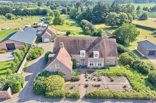 <p><strong>Exclusieve villa met bijgebouwen op 6.660m² grond in Arendonk</strong></p>
<p>Aan de rand van het gezellige dorp Arendonk, op een prachtig perceel van 6.660m², bevindt zich deze subliem afgewerkte villa met luxueuze uitstraling en twee ruime bijgebouwen. De locatie biedt een vlotte verbinding met de E34 (Antwerpen – Eindhoven), alsook tot het centrum van Arendonk.</p>
<p>Indeling & leefruimtes:</p>
<p>Via de royale inkomhal met imposante marmeren trap en vestiaire betreedt u deze stijlvolle woning. De ruime woonkamer met parketvloer en open haard ademt warmte en klasse uit, en biedt dankzij het grote raampartij een prachtig zicht op de verzorgde tuin. Aansluitend bevindt zich de gezellige tuinkamer, eveneens met tuinzicht, en een ingericht bureel – ideaal voor wie thuis werkt.</p>
<p>De volledig ingerichte leefkeuken met ontbijthoek is voorzien van alle comfort en grenst aan een afsluitbaar overdekt terras. Verder vindt u op het gelijkvloers een achterinkom met vaste kasten, ingerichte wasplaats met douche, koele berging en een inpandige dubbele garage met automatische poorten en veel opbergruimte.</p>
<p>Verdieping:</p>
<p>De verdieping biedt twee royale slaapkamers, waaronder een master bedroom met ingerichte dressing en eigen badkamer met bubbelbad, dubbele wastafel, douche en een apart toilet. Daarnaast is er een tweede badkamer met douche, wastafel en toilet. De ruime overloop geeft toegang tot twee zolderkamers die eenvoudig kunnen worden omgevormd tot extra slaapkamers of hobbyruimtes. Via een vlizotrap bereikt u nog een praktische bergzolder.</p>
<p>Bijgebouwen & buitenruimte:</p>
<p>Achter de woning bevinden zich twee kwaliteitsvolle bijgebouwen:</p>
<ul>
<li>Een eerste gebouw van ca. 75 m², opgedeeld in een garage, werkplaats/tuinberging, toilet en open zolder.</li>
<li>Een tweede gebouw van ca. 52 m² met grote automatische poort – perfect voor extra voertuigen of opslag.</li>
</ul>
<p>De fraai aangelegde en volledig omheinde tuin biedt een zee van ruimte en privacy, ideaal voor dierenliefhebbers of wie graag buiten leeft.</p>
<p></p>
<p><strong>Samenvattend</strong></p>
<p>Deze eigendom combineert <strong>ruimte, luxe en functionaliteit</strong> op een unieke locatie in Arendonk. Perfect voor wie houdt van <strong>comfortabel wonen in een groene, rustige omgeving</strong>, met alle faciliteiten binnen handbereik.</p>
<p></p>
<p>Algemeen:</p>
<ul>
<li>Bouwjaar 2001 – architect Michel Rutten;</li>
<li>Grondoppervlakte: 6.660m²; mogelijkheid tot het bijkopen van 3.667m²</li>
<li>Eigen watervoorziening;</li>
<li>Zuid gerichte tuin en terras van 50m² in arduin;</li>
<li>Automatische beregeningsinstallatie;</li>
<li>Airco op 1 slaapkamer;</li>
<li>Overal elektrisch bediende rolluiken aanwezig;</li>
<li>Elektrische vloerverwarming;</li>
<li>…</li>
</ul>
