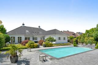 Deze vrijstaande exclusieve villa straalt karakter en comfort uit. Omringd door een fraai aangelegde tuin met verwarmd zwembad en poolhouse biedt deze woning een unieke combinatie van comfort, luxe en ruimte. Dankzij de praktische indeling is wonen op het gelijkvloers perfect mogelijk. De ideale woonplek voor wie houdt van rust en privacy.<br /><br />=> Ligging<br />Deze vrijstaande villa is rustig gelegen in de Derde Straat in Maaseik, een aangename en residentiële buurt. U geniet er van privacy én een vlotte bereikbaarheid. Winkels, scholen en het centrum van Maaseik liggen op korte afstand, terwijl u toch woont in alle rust en groen. <br /><br />=> Gelijkvloers<br />- Royale inkomhal<br />- Apart gastentoilet met fonteintje<br />- Vestiaire <br />- Via de dubbele glazen deur bereikt u de leefruimte<br />- Luchtige leefruimte met veel lichtinval, doorkijk gashaard en toegang tot de tuin<br />- Ingerichte keuken met zicht op en toegang tot het terras<br />- Wasplaats/bijkeuken met vaste kasten en ingebouwde keukentoestellen<br />- Ouderlijke slaapkamer met vaste kasten en ensuite badkamer met ligbad, dubbele wastafel en inbouwkasten<br />- Tweede slaapkamer<br />- Bureelruimte <br />- Dubbel inpandige garage met automatische poorten en extra douchecel<br /><br />=> Verdieping<br />- Overloop met ingebouwde sauna<br />- Derde slaapkamer met douchecel en toilet<br />- Vierde slaapkamer<br />- Technische ruimte met C.V.-ketel op aardgas<br />- Vier zolderruimtes, polyvalent in te richten (hobbyruimte, extra slaapkamers, bureel …)<br /><br />=> Kelder<br />- Kleine voorraadkelder onder de hal<br /><br />=> Tuin<br />- Verzorgde, volledig omheinde tuin rondom de woning<br />- Groot zonneterras met automatische zonneluifel aan de achterzijde<br />- Verwarmd zwembad via warmtepomp<br />- Poolhouse met overdekt terras, ideaal voor ontspanning op zomeravonden<br /><br />=> Indeling:<br />-- Gelijkvloers: inkomhal met vestiaire en apart gastentoilet, woonkamer, keuken, wasplaats/bijkeuken, ouderlijke slaapkamer met ensuite badkamer, tweede slaapkamer, en dubbel inpandige garage;<br />-- Verdieping: overloop met sauna, twee slaapkamers, zolderruimtes en technische ruimte;<br />-- Kelder: voorraadruimte onder de inkomhal.