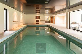 Dans la Veurnelaan à Saint-Idesbald, près des dunes de Houtsaeger, se trouve cette villa très spacieuse et élégante « Les Ramures », située dans un quartier résidentiel sur un terrain unique de pas moins de 2 749 m². Avec une surface habitable d'environ 676 m², cette propriété offre une combinaison exceptionnelle d'espace, de confort et d'intimité.<br />La villa vous accueille dans un hall d'entrée imposant avec vestiaire et toilettes séparées pour les invités. Le grand salon lumineux respire la classe et la chaleur et dispose d'une cheminée, d'un coin salon supplémentaire et d'une salle à manger donnant sur la cuisine semi-ouverte. Les matériaux utilisés, notamment les sols en travertin et les menuiseries en aluminium, soulignent le caractère haut de gamme et intemporel de la villa.<br />La villa compte quatre chambres très spacieuses, dont une chambre principale à l'étage avec dressing, salle de bains luxueuse et toilettes séparées. Il y a également trois chambres au rez-de-chaussée avec une salle de bains rénovée équipée d'une douche à l'italienne, double lavabo et de toilettes. En outre, la villa dispose d'un grand grenier qui offre de nombreuses possibilités, telles que la création de chambres supplémentaires, d'un bureau ou d'une salle de loisirs.<br />La grande piscine intérieure (10 x 5 m), équipée d'une douche, d'un vestiaire, de toilettes et d'un coin salon, est un atout indéniable qui vous offre une expérience de bien-être exclusive chez vous. La villa dispose également d'une cave à vin et d'un grand garage pour deux voitures avec porte automatique.<br />Construite en 1975, elle est équipée de double vitrage et de volets roulants automatiques. Elle a fait l'objet d'une rénovation complète en 1997 et a depuis toujours été très bien entretenue.<br />Le jardin entièrement clôturé et aménagé est orienté sud-ouest et offre un ensoleillement optimal et une grande intimité. Un portail d'accès automatique et plusieurs places de parking sur le terrain complètent le tout.<br />En bref, une villa très spacieuse et pleine de caractère offrant de nombreuses possibilités, idéale pour ceux qui recherchent de l'espace, la tranquillité et un emplacement prestigieux sur la côte belge. EPC : 567 kWh/m². Prix demandé : 1 850 000 €.