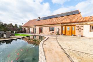 *** TE KOOP *** Rebecq - Bierghes - Charmante villa in boerderijstijl met 4 slaapkamers, een tuin en een ruime garage, ideaal gelegen in een rustige omgeving, met een totale oppervlakte van ongeveer 364 m². Op de begane grond is de indeling als volgt: een inkomhal, een volledig ingerichte open keuken (koelkast met vriesvak, oven, magnetron, afzuigkap, vaatwasser, keramische kookplaat en granieten werkblad) van ± 22 m², een ruime woonkamer van ± 47 m² met open haard (Brisach), een master suite van ± 22 m² met een eigen badkamer (hoekbad met hydromassage, inloopdouche, wastafelmeubel &amp; toilet), een wasruimte van ± 18 m²  en een apart toilet. Op de verdieping: via een eerste overloop, een slaapkamer van ± 26 m² met eigen badkamer. Via een tweede nachthal, twee slaapkamers van ± 15 en 14 m², elk met een eigen badkamer, een ruime multifunctionele ruimte van ± 47 m² en een apart toilet.<br /><br />Comfort: EPC “C” (197 kWh/m²/jaar). Grote garage van ± 100 m² met een gemotoriseerde sectionaaldeur, evenals 6 parkeerplaatsen buiten. Achterterrein met een mooie omheinde tuin, ideaal gelegen op het zuidoosten. Terras van ± 38 m², aangevuld met een tuinhuisje, een serre en een gezellige vijver. Houten kozijnen met dubbele beglazing. Verwarming met omkeerbare warmtepomp + stookolie. Installatie van 24 zonnepanelen. Elektrische poort met videofoon. Aanwezigheid van een zuiveringsinstallatie van 10.000 L.<br /><br />Prijs: V.O. vanaf 675.000 euro (onder voorbehoud van goedkeuring door de eigenaar)<br /><br />Contact: tubize@weinvest.be of tel. 02.355.42.20 of Julie op 0472.53.66.84