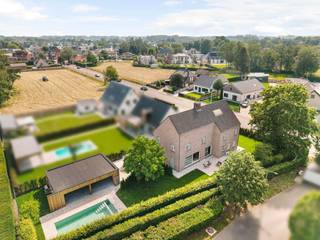 Landelijke woning met praktijkruimte gelegen nabij het centrum van Hoogstraten op perceel van 967 m². De woning werd gebouwd in 2005 en biedt verrassend veel ruimte. Ideaal voor wonen in combinatie met vrij beroep of kantoorruimte aan huis. <br /><br />Gelijkvloers: <br />U betreedt de inkomhal van de woning via de zijkant van het gebouw. In de inkomhal hebt u een gastentoilet. De woonkamer is aan de achterzijde gesitueerd en omvat een ruime zit- en eethoek op parket. De keuken bevindt zich aanpalend en is gescheiden via een speksteenkachel met ingebouwde pizza-oven. Vanuit de leefkeuken kunt u via grote schuifpuien naar het terras aan de zij-kant (zuid-westen). Aan het keukeneiland met vaste eettafel kunt u heerlijk tafelen. De keuken is uitgerust met modern apparatuur en natuurstenen werkblad. Handige wasplaats/berging met inbouwkasten bevindt zich aanpalend, alsook hebt u vanuit de keuken toegang tot de kelderruimte.<br /><br />Praktijkruimte: <br />De praktijkruimte is toegankelijk via afzonderlijke inkomhal aan de voorkant van het gebouw. Rechts hebt u een kleine wachtkamer met toilet. Rechts een mooie praktijkruimte met vast bureau en inbouwkasten. De praktijkruimte is eveneens toegankelijk vanuit de privé. <br /><br />Eerste verdieping: <br />Vaste trap vanuit de keuken naar de bovenverdieping op laminaat. Hier treft u de masterbedroom aan de achterzijde, dewelke is voorzien van vele inbouwkasten. Verder nog 4 slaapkamers, allen voorzien van inbouwkasten/vast meubilair. De badkamer is ruim en praktisch voor een groot gezin en omvat een douche, ligbad, dubbele lavabo in meubel en een toilet. <br /><br />Tweede verdieping: <br />Via een afzonderlijke ruimte hebt u een vaste trap naar de zolderverdieping. Hier hebt u een ruime bergzolder met de CV installatie en verder nog 2 afzonderlijke slaap-/hobbyruimtes.<br /><br />Tuin en garage: <br />Apart garagegebouw in de tuin, toegankelijk via oprit aan de zijkant naar achter. Net als onder de woning is ook hier kruipruimte voorzien. Poolhouse aansluitend met naastliggend vernieuwd zwembad. Zwembadinstallatie aanwezig in garage. Mooi terras aan de zijkant van de woning (zuid-west). <br /><br />Bijzonderheden: <br />- nabij centrum van Hoogstraten, in onmiddellijke nabijheid van supermarkt en voorzieningen. <br />- ideaal voor combinatie wonen / werken aan huis<br />- verwarming op aardgas (condensatieketel 2017) dmv radiatoren <br />- verrassend ruime woning met veel volume<br />- regenwaterput - aangesloten op toiletten / wasmachine<br />- gunstig EPC label - B