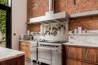 Deze eigenzinnige woning is ontstaan uit een herenhuis, versmolten met een nieuwbouwwoning. U geniet dus van de prachtige stijl van een herenhuis in het comfort en ruimtelijkheid van een nieuwbouw, met grote glaspartijen, veel lichtinval en een zeer ruime tuin. <br /><br />U komt binnen via de oude woning met prachtige authentieke elementen en geniet onmiddellijk van het comfort van de nieuwbouwwoning met zeer hoge plafonds en een grote raampartij die rechtstreeks uitkomt op de tuin. De breedte van de tuin is 11 meter, ingericht in Piet Oudolfstijl, waardoor je midden in de stad kan genieten van een eigentijdse oase van groen. <br /><br />Omdat de woning meer dan 500m² omvat beschikt u over een grote leefruimte met geïnstalleerde keuken, aangrenzend aan de tuin. Via zwevende betonnen treden komt u in de living. In dit (nieuwbouw) gedeelte van de woning vindt u ook nog drie slaapkamers en een badkamer en dressing. Naast de keuken bevindt zich een grote garage (40m²). Als je in de inkomhal de trap omhoog neemt, komt u in een apart gedeelte van de woning met nog eens vier slaapkamers, twee badkamers, een leefruimte met keuken en een dakterras met prachtig zicht op de stad, dit gedeelte staat volledig los van de andere delen van de woning en wordt momenteel in co-housing gebruikt. De woning is ontworpen door de architecten 'Verdickt &amp; Verdickt '.Ideaal als praktijk of kantoorruimte. <br /><br />De omgeving van de Oude Steenweg bevindt zich in een stukje Antwerpen in volle ontwikkeling, vlakbij de Paardenmarkt via waar je op wandelafstand bent van zowel het toeristische centrum als het bruisende Eilandje. De wijk Dam met park Spoor Noord en de vernieuwde slachthuissite bevindt zich ook op wandelafstand. Aan de woning zelf zijn er volop winkels en openbaar vervoer.