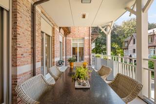 Uitzonderlijk villa-appartement van ca. 330 m²! <br />Een zeldzame combinatie van de ruimte en grandeur van een royale villa met het comfort, de privacy en het onderhoudsgemak van residentieel wonen. De statige architectuur, fraai aangelegde tuinen en hoogwaardige afwerking onderstrepen het exclusieve karakter van het geheel. Met zijn uitzonderlijke woonoppervlakte, royale buitenruimtes en bijzonder doordachte indeling, is dit appartement het absolute topsegment van Schilde.<br /><br />Indeling:<br />De privatieve inkomhal met vestiaire en toilet, vormt meteen een stijlvolle introductie en geeft via elegante stalen binnendeuren toegang tot de leefruimtes.<br /><br />Centraal bevindt zich de uitzonderlijk royale woonkamer van ca. 90 m², opgedeeld in verschillende harmonieus verbonden leefzones met een formele eetkamer, ruim salon rond de gashaard en bijkomende zit- en leeshoeken. Hoogwaardig maatwerk, warme parketvloeren en talrijke raampartijen zorgen voor een tijdloze en verfijnde sfeer.<br /><br />De ruime leefkeuken van ca. 38 m² vormt een tweede volwaardige leefruimte en werd uitgerust met een groot centraal eiland, natuurstenen werkbladen, uitgebreid maatwerk en hoogwaardige Miele-toestellen. De geïntegreerde eetplaats, eveneens met gashaard, sluit rechtstreeks aan op het grotendeels overdekte terras van ca. 26,9 m². Een praktische bijkeuken/berging vervolledigt deze zone.<br /><br />De master suite vormt een bijzonder private vleugel met een royale slaapkamer van ca. 37 m², een volledig op maat ingerichte dressing van ca. 18 m² en een luxueuze badkamer met dubbele wastafel, inloopdouche en lig-/whirlpoolbad. De slaapkamer geeft rechtstreeks toegang tot de buitenruimtes aan de achterzijde.<br /><br />Een 2e ruime slaapkamer beschikt over maatwerk, een eigen balkon en een afzonderlijke badkamer met inloopdouche. Het aparte bureau van ca. 25,5 m² aansluitend aan de woonkamer, kan dankzij zijn royale afmetingen perfect opnieuw als 3e slaapkamer worden ingericht.<br /><br />Verspreid over verschillende zijden beschikt het appartement over vijf terrassen en balkons, samen goed voor ca. 62 m² buitenruimte. Vooraan geniet men van een ruime en beschutte buitenkamer aansluitend aan de leefkeuken, terwijl de terrassen achteraan uitkijken over het volwassen groen van het domein.<br /><br />Bijzonderheden:<br />- Ca. 330 m² bewoonbare oppervlakte<br />- Uitzonderlijk royale leefruimte van ca. 90 m²<br />- Leefkeuken van ca. 38 m² met Miele-toestellen<br />- 2 slaapkamers + bureau / mogelijkheid tot 3 slaapkamers<br />- 2 badkamers<br />- Master suite met ruime dressing<br />- Ca. 62 m² terrassen en balkons<br />- Afgesloten garagebox voor 2 grote wagens met extra bergruimte<br />- Afzonderlijke privatieve kelderberging<br />- Hoogwaardig maatwerk en tijdloze afwerking<br />- EPC-label A