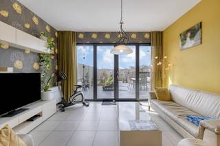 Dit appartement biedt een ruim bewoonbare oppervlakte van 136 m², een praktische indeling en een fantastisch terras.<br /><br />Met een zuidwestgericht terras van maar liefst 108 m² geniet u hier optimaal van de middag- en avondzon. Het terras is volledig omheind en voorzien van een praktische zonneluifel. Via het tuinpoortje wandelt u bovendien zo naar de garage en de fietsenberging.<br /><br />Binnen is het appartement hoogwaardig en functioneel afgewerkt:<br />- Woonkamer met airconditioning voor warme zomerdagen<br />- Keuken voorzien van Miele-toestellen en een Dovy-dampkap.<br />- Twee slaapkamers met massief eiken binnendeuren en ingebouwde kasten tot aan het plafond.<br />- Badkamer met een ligbad, een aparte douche en een dubbel lavabomeubel.<br /><br />Het appartement is uitgerust met energiezuinige technieken zoals geothermie, een warmtepomp en eigen zonnepanelen. Dit zorgt voor een comfortabel binnenklimaat en een beheersbaar energieverbruik.<br /><br />De belangrijkste troeven op een rij:<br />- Groot, zonnig terras (108 m²) met goede privacy.<br />- Bouwjaar 2014, voorzien van driedubbel glas, rolluiken en vliegramen.<br />- Lage syndickosten<br />- Mogelijkheid om een bijhorende garage aan te kopen<br /><br />Deze AI-visualisaties zijn bedoeld als inspiratie. Er werd geen rekening gehouden met technische specificaties, stedenbouwkundige voorschriften of de concrete mogelijkheden tot realisatie.