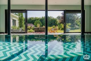 <p><span>Luxe villa op een residentiële locatie, grenzend aan natuurgebied, op een perceel van 8.492 m². De villa beschikt over o.a. 5 slaapkamers, 3 badkamers, een hoogwaardige wellnessruimte met een inpandig overloopzwembad en een garage voor 2 wagens. Het eigendom biedt optimale privacy en rust in een prachtig aangelegde tuin, een unieke plek voor ultieme ontspanning. </span></p><p><span> </span></p><p><span> </span></p><p><span>Gelijkvloers<br /></span><span>Imposante entree middels een grote staal / glazen deurpartij naar de centrale open inkom die in directe verbinding staat met de leefruimte en een prachtige doorkijk biedt naar de achtertuin, aan de linkerzijde bevindt zich een ruime zitkamer met een unieke open haard en ingebouwde TV, de grote ramen bieden een mooi zicht op de tuin en een aansluitende aparte ruimte die kan dienen als TV-kamer, bureel of bibliotheek.  Aan de overzijde van de zitkamer bevindt zich een moderne luxe keuken voorzien van alle hedendaagse (Gaggenau) inbouwapparatuur met een directe verbinding tot het terras. Aangrenzende eetkamer met ingebouwde kasten, momenteel in gebruik als speelkamer.<br />Nachthal die uitgeeft op de masterbedroom bestaande uit een slaapkamer, dressingkamer en luxe badkamer die ook toegang biedt tot de zwembadruimte en een extra slaap / hobbykamer met badkamer. Doorgang met ingemaakte kasten naar de wasplaats. <br />Inpandige garage die ruimte biedt voor twee wagens en voorzien van een automatische poort. </span></p><p><span> </span></p><p><span>Wellnessruimte<br /></span><span>Grote ontspannings- en wellnessruimte met een inpandig overloop zwembad, jaccuzzi, stoombad, kleedruimte, sanitair etc. Vanuit de zwembadvleugel zicht en directe toegang tot de tuin en terras. </span></p><p><span><br />Eerste verdieping</span><span><br />De nachthal op de eerste verdieping geeft uit op 3 slaapkamers, een badkamer en een bergzolder. </span></p><p><span><br />Kelder</span><span><br />Kelder onderverdeeld in een bergruimte en een wijnkelder. </span></p><p><span><br />Tuin en buitenruimtes</span><span> <br />Fraai aangelegde en zeer open tuin die volledige rust en privacy biedt.  Meerdere terrassen, waaronder ook een overdekt terras met verwarming. <br />De tuin heeft een siervijver, bloementuin, fontein, tuinverlichting, beregening, etc, alle comfort is voorzien.</span></p><p><span> </span></p><p><span>Bijzonderheden<br /></span><span>- Unieke trendy en luxueuze villa met lichte en ruime leefruimtes</span></p><p><span>- Recent gerenoveerd, o.a. keuken, badkamers, vloeren, installaties (warmtepomp, energiezuinige zwembadinstallaties, ….)</span></p><p><span>- Volwaardige wellnessruimte </span></p><p><span>- Recht tegenover het uitgestrekte natuurgebied De Uitlegger en het Militaire domein </span></p><p><span>- Beveiligd met o.a. inbraakwerende beglazing , uitgebreid alarmsysteem, camerabewaking, …. </span></p><p><span> </span></p><p><span> </span></p>