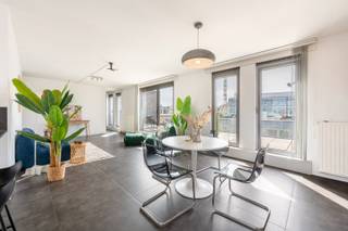 Deze instapklare penthouse is gelegen in de Lange Sint-Annastraat, een karaktervolle straat in het hart van Antwerpen, op het kruispunt van het Eilandje, de universiteitswijk en het historische centrum. Stijlvolle winkels, kwalitatieve horeca en culturele hotspots bevinden zich op wandelafstand, net als de Meir, Groenplaats en Grote Markt. Dankzij deze centrale ligging geniet u van het bruisende stadsleven, terwijl u bovenaan het gebouw in alle rust thuiskomt. Zowel openbaar vervoer als belangrijke invalswegen zijn vlot bereikbaar.<br /><br />Het appartement bevindt zich op de bovenste verdieping van een recente en verzorgde residentie. De lichtrijke leefruimte vormt het hart van het appartement en geeft via grote raampartijen toegang tot twee ruime zonneterrassen aan weerszijden. Dit zorgt de hele dag door voor overvloedig natuurlijk licht en een aangenaam panoramisch uitzicht over de stad. Aansluitend aan de leefruimte bevindt zich een aparte bureauruimte, ideaal als thuiswerkplek of in te richten als derde slaapkamer.<br /><br />De keuken is volledig uitgerust met kwalitatieve toestellen en een ruim werkblad, perfect voor wie graag kookt en gasten ontvangt. Verder beschikt het appartement over twee ruime slaapkamers, een modern afgewerkte badkamer met ligbad, inloopdouche en dubbel lavabomeubel, een apart gastentoilet en een praktische (was) berging. <br />Een privatieve kelderberging en gemeenschappelijke fietsenberging zijn inbegrepen. De aankoop van een ondergrondse autostaanplaats is mogelijk.
