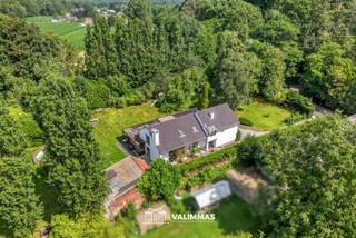 VALIMMAS verkoopt deze zeer ruime alleenstaande woning, met prachtige en ideaal georiënteerde tuin, op ± 38 are...
Het gelijkvloers bestaat uit een inkomhal, een toilet, een bureel (±44m², thans in twee aparte burelen/kamers verdeeld), een grote living (± 54m²) met open haard, een veranda/leefruimte (± 42m²), een volledig ingebouwde keuken met bijkeuken/wasplaats, en een garage voor twee wagens.
De verdieping herbergt een overloop/nachthal met inbouwkasten, een toilet, een master bedroom (± 30m²) met uitzicht op de tuin, drie mooie slaapkamers, een badkamer met ligbad en inloopdouche, en een badkamer met douche.
Achteraan, in een apart bijgebouw, zit een atelier/hobbyruimte (± 35m² + zolder) en een tuinberging met de pomp/filterinstallatie van het zwembad (± 9 x 4m). Rondom ligt een prachtig aangelegde tuin met gazon, terras, bomen, sieraanplantingen, hagen....
Achterin gelegen woning op groot perceel in residentiële buurt Oude Baan/Brukersebaan, met gemakkelijke verbindingen naar Aalst, Ternat, Asse, E40, diverse KMO-zones, …