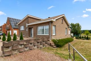 Deze gezinswoning heeft een fantastische bereikbaarheid op slechts 1km van de oprit van de E314 en winkel, bushalte, school, restaurant en bank liggen ook allen binnen de kilometer. De woning is gelegen op 23a 42ca en heeft een Zuid-gerichte tuin met zicht op het groen. De ramen werden reeds vervangen door PVC exemplaren met dubbele beglazing en er zijn overal rolluiken. De indeling is als volgt: we betreden de woning via de inkomhal, met links het toilet, er is een ruime woon- en eetkamer van 32m², een ingerichte keuken en een veranda. Wanneer we 6 trapjes naar boven gaan vinden we 3 slaapkamers en een badkamer terug. Eén van de slaapkamers is momenteel voorzien van een inloopdouche. De woning heeft een ruime, betegelde kelder en een inpandige garage. Buiten is er nog een tweede garage en parkeergelegenheid voor ongeveer 5 wagens. Aansluitend zijn er nog tuinbergingen voorhanden. Maak uw afspraak ter plaatse en laat u overtuigen.