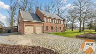 <strong>LEDE – Ruime villa met karakter op een ruim perceel</strong><br /><br />In het hart van Lede, op een rustige doch centraal gelegen ligging, treft u deze statige villa uit 1975, opgebouwd in traditioneel metselwerk en omgeven door een indrukwekkend perceel van 37a 84ca en palend aan agrarisch gebied. Bij binnenkomst wordt u verwelkomd in een centrale traphal die meteen toegang biedt tot de lichte en karaktervolle woonkamer. Grote raampartijen overspoelen de ruimte met natuurlijk licht en accentueren het tijdloze karakter van de woning, versterkt door massieve houten balken. De benedenverdieping biedt naast de woonkamer een aparte keuken, een bureau, een ruime berging en een zeer grote garage.<br /><br />Op de bovenverdieping bevinden zich zes ruime slaapkamers, waarvan drie zijn uitgerust met een eigen wasbak, aangevuld met een badkamer voorzien van ligbad, douche en dubbele wastafels. Extra comfort wordt geboden door een zeer ruime zolder die momenteel als stockage wordt gebruikt en een kruipkelder. In 2025 is een moderne aardgasverwarming geplaatst, waardoor comfort en energie-efficiëntie hand in hand gaan.<br /><br />De buitenruimte maakt deze villa uniek: een weelderig perceel met tal van volwassen bomen, een natuurlijke vijver en voorzieningen voor dieren, waaronder twee stallen en een aansluitende stockageruimte, naast een extra buitenberging. Deze woning combineert statige elegantie met praktische ruimte en een groene, rustgevende omgeving, terwijl scholen, winkels en verbindingswegen binnen handbereik liggen.<br /><br />Ontdek zelf deze prachtige villa en bel voor een afspraak op 053/60.65.66.<br />De prijs is een niet-bindende richtprijs. Na biedingen beslist de verkoper over verkoop aan het beste bod. Info via ons of reglement.