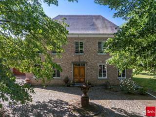 Wie op zoek is naar ruimte, rust en veelzijdigheid, voelt zich hier meteen thuis. Deze uitzonderlijke vrijstaande woning is gelegen op een prachtig perceel van maar liefst 8.392 m² en combineert royale volumes met privacy, comfort en een uniek groen kader.<br /><br />De woning wordt omgeven door een schitterende, volwassen en perfect georiënteerde zuidgerichte tuin, waar je in alle rust geniet van zon, natuur en een weids uitzicht op het omliggende groen. De ruime oprit en garage zorgen bovendien voor optimaal praktisch comfort en voldoende parkeergelegenheid.<br /><br />Binnen verwelkomt de woning je met bijzonder royale leefvolumes en een doordachte indeling. <br />De woning beschikt over 4 bijzonder ruime slaapkamers, elk met veel lichtinval en tal van indelingsmogelijkheden. De badkamer is volledig uitgerust en biedt alle comfort met zowel een ligbad als een douche.<br /><br />Een extra troef is de ruime zolderverdieping, bereikbaar via een vaste trap. Deze polyvalente ruimte biedt nog tal van mogelijkheden en kan perfect ingericht worden als extra slaapkamers, hobbyruimte, bureau of ontspanningsruimte.<br /><br />De inpandige dubbele garage heeft nog een bijkomende zolder die ook nog volledig ingericht kan worden. <br /><br />Naast het hoofdgebouw is er nog een bijgebouw dat volledig voorzien is van keuken en badkamer en mogelijkheid bied voor uitbreiding van 1 naar 3 slaapkamers. <br /><br />Dit eigendom biedt een uitzonderlijke flexibiliteit en is ze uitermate geschikt voor cohousing, kangoeroewonen, een praktijk aan huis of het comfortabel samenwonen van meerdere generaties.<br /><br />Daarnaast biedt deze woning ook energetisch nog interessante opportuniteiten: met een beperkte investering kan het EPC aanzienlijk verbeterd worden. Bij de plaatsing van een warmtepomp en het verwijderen van de houtkachel kan de EPC-score stijgen naar begin label B, wat een mooie meerwaarde betekent voor de toekomstige eigenaar.<br /><br />Contacteer Vincent voor een bezoek ter plaatse via 0475 21 00 86 of Vincent@reds.be.