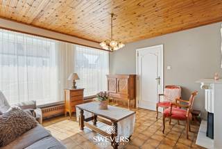 Voor meer info en foto’s, surf naar www.swevers.be – Deze ruime halfopen woning aan Huzarenstraat 18 in Lummen biedt 178 m² bewoonbare oppervlakte, vier slaapkamers, een grote garage en een aangename tuin. De woning dateert van 1957 en is te renoveren, waardoor je ze volledig naar eigen smaak kunt inrichten. In 2016 werden de ramen vernieuwd en overal rolluiken geplaatst. Op het gelijkvloers vind je een inkomhal, een woonkamer van 24 m², een keuken van 10 m² en een ruime veranda die rechtstreeks aansluit op de tuin. Verder zijn er een berging en een garage van 30 m². De eerste verdieping telt drie slaapkamers van 20 m², 9 m² en 9 m², een badkamer en een apart toilet. Via een vaste trap bereik je de tweede verdieping met een vierde slaapkamer van 15 m² en een afzonderlijke zolderruimte. Een kelder van 15 m² zorgt voor bijkomende opslag. Het perceel van 3a 83ca heeft een noordwestelijke oriëntatie en beschikt over een ruime, aangelegde tuin. Dankzij de veranda, garage en verschillende bergruimtes biedt de woning heel wat praktisch potentieel. Ook de ligging is een troef: rustig en toch vlak bij het centrum van Lummen. Scholen, openbaar vervoer, winkels, horeca en sportfaciliteiten bevinden zich op wandelafstand. De snelweg ligt op ongeveer 1,25 km. Een interessante renovatiekans voor wie op zoek is naar ruimte, een tuin en vier slaapkamers op een praktische locatie. Voor meer informatie, bel 011 255 155. Bron bewoonbare oppervlakte: EPC – verslag. Dit pand is onderworpen aan de renovatieverplichting van de Vlaamse overheid voor residentiële gebouwen (behoudens bij sloop binnen 5 jaar na de aankoop). Consulteer voor meer informatie de website van het Vlaams Energie- en Klimaatagentschap via https://www.vlaanderen.be/een-huis-of-appartement-kopen/renovatieverplichting-voor-residentiele-gebouwen.