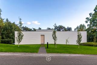 In de exclusieve woonparkomgeving van Bolderberg bevindt zich deze modernistische villa naar de hand van architect Francis Strauven, een meesterwerk van licht, rust en geavanceerde technologie. De in 2014 gerenoveerde eigendom onderscheidt zich door een hoogwaardige afwerking met materialen zoals massief noestenvrij parket, natuursteen en designaccenten van Antonio Lupi en Vola.<br />Het interieur vloeit naadloos over in de groene omgeving dankzij kamerhoge raampartijen met driedubbele beglazing. De woning biedt drie ruime slaapkamers en twee luxueuze badkamers, verdeeld over het gelijkvloers en het functionele souterrain, waar ook een privé-sauna en een garage voor drie wagens zijn ondergebracht. De Bulthaup-keuken met V-Zug toestellen vormt het culinaire hart van de woning, terwijl technieken zoals een geothermische warmtepomp, PV-panelen en een geavanceerd ventilatiesysteem zorgen voor een ongeëvenaard wooncomfort.<br />Buiten geniet u op het zuidgerichte perceel van bijna 30 are van optimale privacy en een weids zicht. Met een royaal arduinen terras en reeds aanwezige voorzieningen voor een zwembad, biedt dit domein alle ruimte voor een exclusieve levensstijl op een absolute toplocatie.