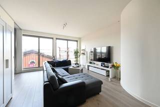 In de levendige wijk Het Eilandje, pal tegenover het iconische Red Star Line-museum, vind je dit prachtige appartement in Residentie Liberty. Een creatie van AWG Architecten, waar tijdloze architectuur en modern wooncomfort naadloos samenvloeien.Dit recent gebouw uit 2018 huisvest een energiezuinig appartement (EPC-label A) op de tweede verdieping, met een oppervlakte van 94 m². De grote raampartijen zorgen voor een overvloed aan natuurlijk licht, terwijl de indeling optimaal benut wordt. De ruime leefruimte sluit aan op een moderne open keuken, volledig uitgerust en ontworpen voor hedendaags gemak. In de aparte berging is er plaats voor wasmachine en droogkast, en de badkamer is uitgerust met een ruime inloopdouche en dubbel lavabomeubel.Met twee comfortabele slaapkamers en een zuidgericht terras van 13m² biedt deze woonst een perfecte balans tussen stadse dynamiek en rust. Parkeren is bovendien geen probleem: er is een ondergrondse staanplaats beschikbaar voor aankoop (€40.000).