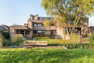 <br />In een uitzonderlijke groene omgeving, op een royaal perceel van 4.351 m², bevindt zich deze architecturale villa, ontworpen door Jos Van Driessche en opgetrokken in 2009. De invloed van Frank Lloyd Wright is duidelijk aanwezig in de horizontale lijnen, de open zichten en de harmonieuze inpassing in het landschap. Dit is een woning die niet alleen indruk maakt door haar immense ruimte, maar ook door haar unieke architecturale signatuur.<br /><br />Met een bewoonbare oppervlakte van 650 m² en een volledig bruikbare kelderverdieping van 304 m² biedt deze villa een uitzonderlijk wooncomfort. De inkomhal met gastentoilet leidt naar een aparte bureauruimte, twee ruime leefruimtes, een lichtrijke eetplaats en een volledig uitgeruste keuken. Daarnaast is er een praktische wasruimte en een dubbele garage.<br /><br />De woning beschikt over vier volwaardige slaapkamers en twee badkamers op de eerste verdieping. Verder kan u genieten van een aparte ruimte waar een sauna en douche is voorzien. De tweede verdieping biedt op heden een vijfde slaapkamer en bijkomende mogelijkheden voor extra kamers of een hobbyruimte.<br /><br />De volledige woning is voorzien van twee trappen aan beide zijden van de woning wat ervoor zorgt dat de woning tevens kan dienen als kangoeroewoning.<br /><br />Wat deze woning écht uniek maakt, zijn de onvervalste vergezichten op het omliggende groen en het beschermd zicht op de Schelderomolen, wat zorgt voor een blijvend gevoel van ruimte en rust doorheen de woning en de tuin. Maak de tuin compleet met een zwembad waardoor u in de zomerperiode kan genieten van vakantie in eigen land. De hoogwaardige materialen, de zorgvuldig uitgevoerde details en de uitzonderlijke architectuur tillen deze villa naar een niveau dat zelden op de markt komt.