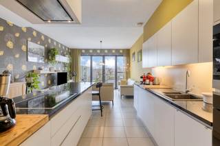Dit appartement biedt een ruim bewoonbare oppervlakte van 136 m², een praktische indeling en een fantastisch terras.<br /><br />Met een zuidwestgericht terras van maar liefst 108 m² geniet u hier optimaal van de middag- en avondzon. Het terras is volledig omheind en voorzien van een praktische zonneluifel. Via het tuinpoortje wandelt u bovendien zo naar de garage en de fietsenberging.<br /><br />Binnen is het appartement hoogwaardig en functioneel afgewerkt:<br />- Woonkamer met airconditioning voor warme zomerdagen<br />- Keuken voorzien van Miele-toestellen en een Dovy-dampkap.<br />- Twee slaapkamers met massief eiken binnendeuren en ingebouwde kasten tot aan het plafond.<br />- Badkamer met een ligbad, een aparte douche en een dubbel lavabomeubel.<br /><br />Het appartement is uitgerust met energiezuinige technieken zoals geothermie, een warmtepomp en eigen zonnepanelen. Dit zorgt voor een comfortabel binnenklimaat en een beheersbaar energieverbruik.<br /><br />De belangrijkste troeven op een rij:<br />- Groot, zonnig terras (108 m²) met goede privacy.<br />- Bouwjaar 2014, voorzien van driedubbel glas, rolluiken en vliegramen.<br />- Lage syndickosten<br />- Mogelijkheid om een bijhorende garage aan te kopen<br /><br />Deze AI-visualisaties zijn bedoeld als inspiratie. Er werd geen rekening gehouden met technische specificaties, stedenbouwkundige voorschriften of de concrete mogelijkheden tot realisatie.