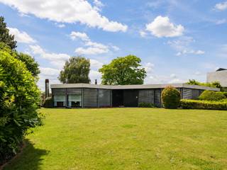 <strong>Oudenaarde</strong><strong> </strong><strong>– Architectenwoning van Guy Van Heuverswyn.</strong><br /><br /><span><span><span><span><span><u>Ruime jaren 70-bungalow, geïnspireerd op het <em>Case Study House Program</em>, met de mogelijkheid tot een combinatie van wonen en werken, een prachtige tuin en achterliggende landbouwgrond.</u></span></span></span></span></span><br /><br /><span><span><span><span><span><em>Voor meer informatie, mail naar info@carloeggermont.be.</em></span></span></span></span></span><br /><br /><span><span><span><span><span>Deze op te frissen architectenwoning met een bruto vloeroppervlakte van maar liefst 323 m² bevindt zich op een zeer bereikbare en zichtbare locatie, nabij de verbindingsweg N60 en het centrum van Oudenaarde.</span></span></span></span></span><br /><br /><span><span><span><span><span>De gunstige, alsook commerciële, ligging gecombineerd met de indeling van de woning, biedt uitstekende mogelijkheden voor een combinatie van wonen en werken.</span></span></span></span></span><br /><span><span><span><span><span>Deze bungalow wordt gekenmerkt door een efficiënte en modernistische bouwvisie, geïnspireerd op de principes van de <em>Case Study Houses</em>. Het grondplan is opgebouwd uit zeshoeken binnen een modulair bouwsysteem, wat zorgt voor een grote mate van flexibiliteit en tal van indelingsmogelijkheden.</span></span></span></span></span><br /><br />Zelfs voor de tuinberging werd dezelfde bouwwijze verdergezet om de uniformiteit te garanderen.<br /><br />Deze ruime woning bevindt zich op een prachtig perceel van maar liefst 2.412 m² en beschikt onder meer over drie slaapkamers, een voormalige bureauruimte met wachtkamer, een tekenkamer en een inpandige garage voor twee wagens.<br /><br />We betreden de woning langs een unieke inkomhal de woning opdeelt in enerzijds het voormalige professionele deel en anderzijds het woongedeelte.<br />Deze hal geeft plaats aan een ruime bureau (potentieel slaapkamer) en aan de overzijde de wachtkamer. Achtergelegen vinden we de voormalige tekenkamer, die alsook kan ingericht worden als slaapkamer.<br /><br />Gekoppeld aan deze inkomhal hebben we een tweede hal die enerzijds licht brengt dankzij de dakkoepel maar die voor de verbindingen zorgt tussen de de verschillende ruimtes in de woning.<br /><br />Hieraan gekoppeld vinden we een bijzonder architecturale leefruimte met haard en bar en zicht op zowel de voor- als de achtertuin, omringd door groen. Naastgelegen hebben we de originele keuken, die vooruitstrevend was voor zijn tijd.<br /><br />Een ruime hal met op maat gemaakte kasten leidt ons naar 3 slaapkamers, 2 badkamers waaronder 1 met een sauna, toegang tot de wasplaats, toegang tot de kelder en als laatste naar een dubbele inpandige garage.<br /><br />Als extra troef bestaat de mogelijkheid om de achterliggende landbouwgrond van 3.238 m² aan te kopen.<br /><br /><span><span><span><span><span><strong>Kortom, een bijzondere opportuniteit voor liefhebbers van architectuur.</strong></span></span></span></span></span><br />